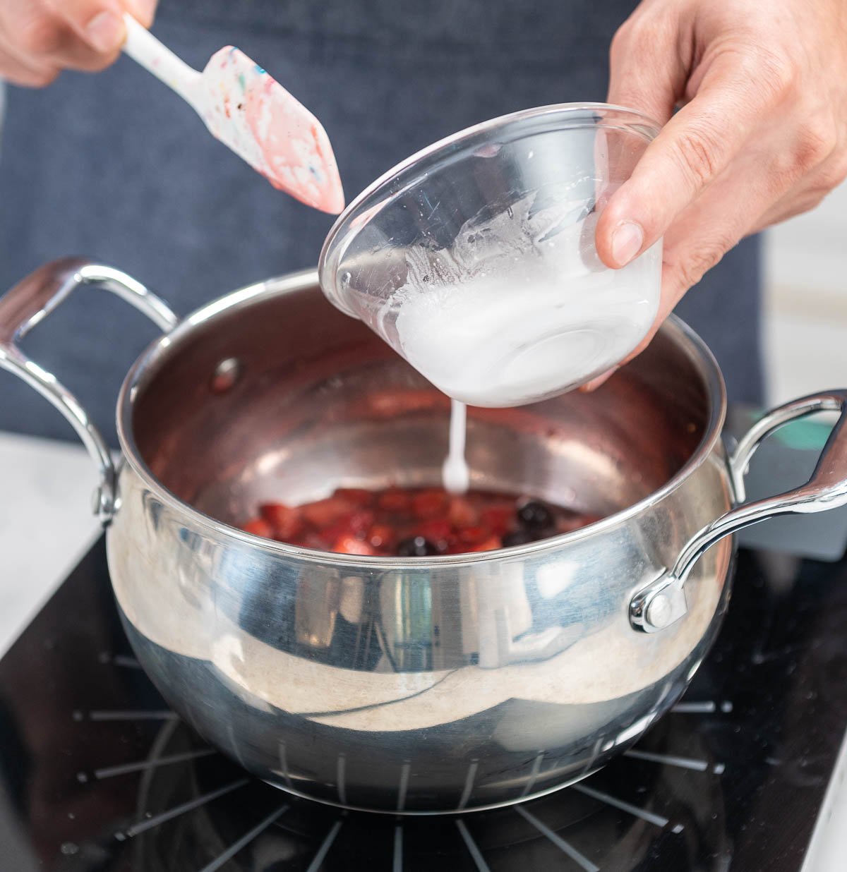 hand shown pouring mixture into berry sauce