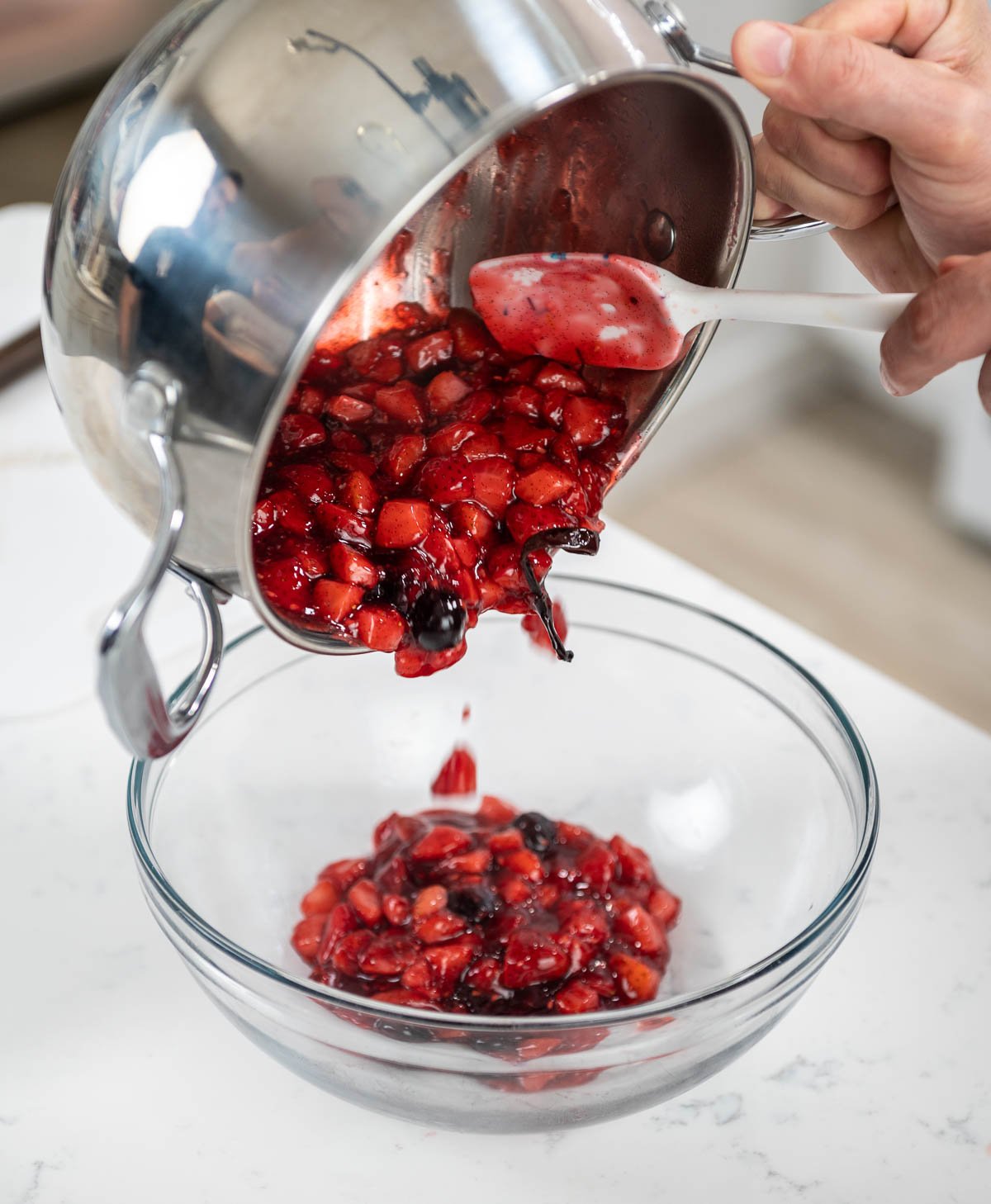pouring berry sauce mixture into a bowl