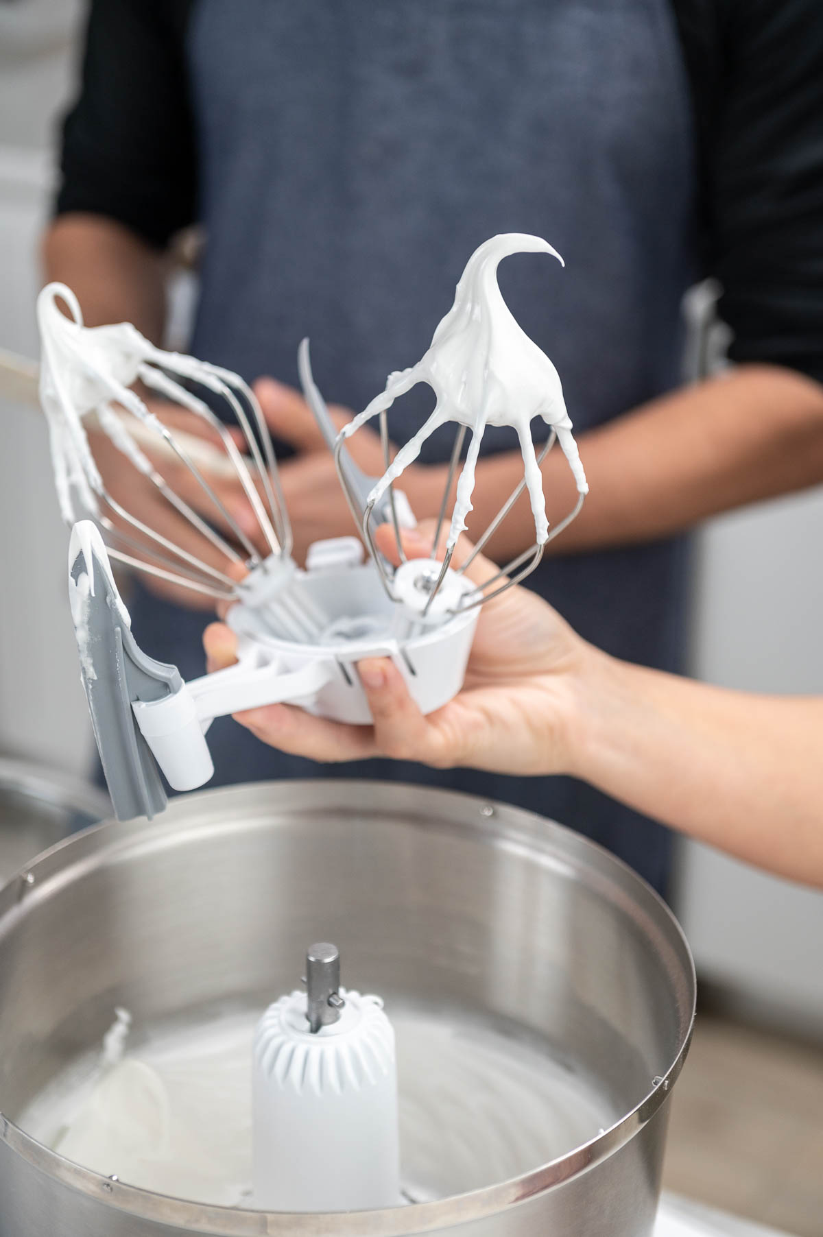 hand holding whisk attachment with cream on it upside down