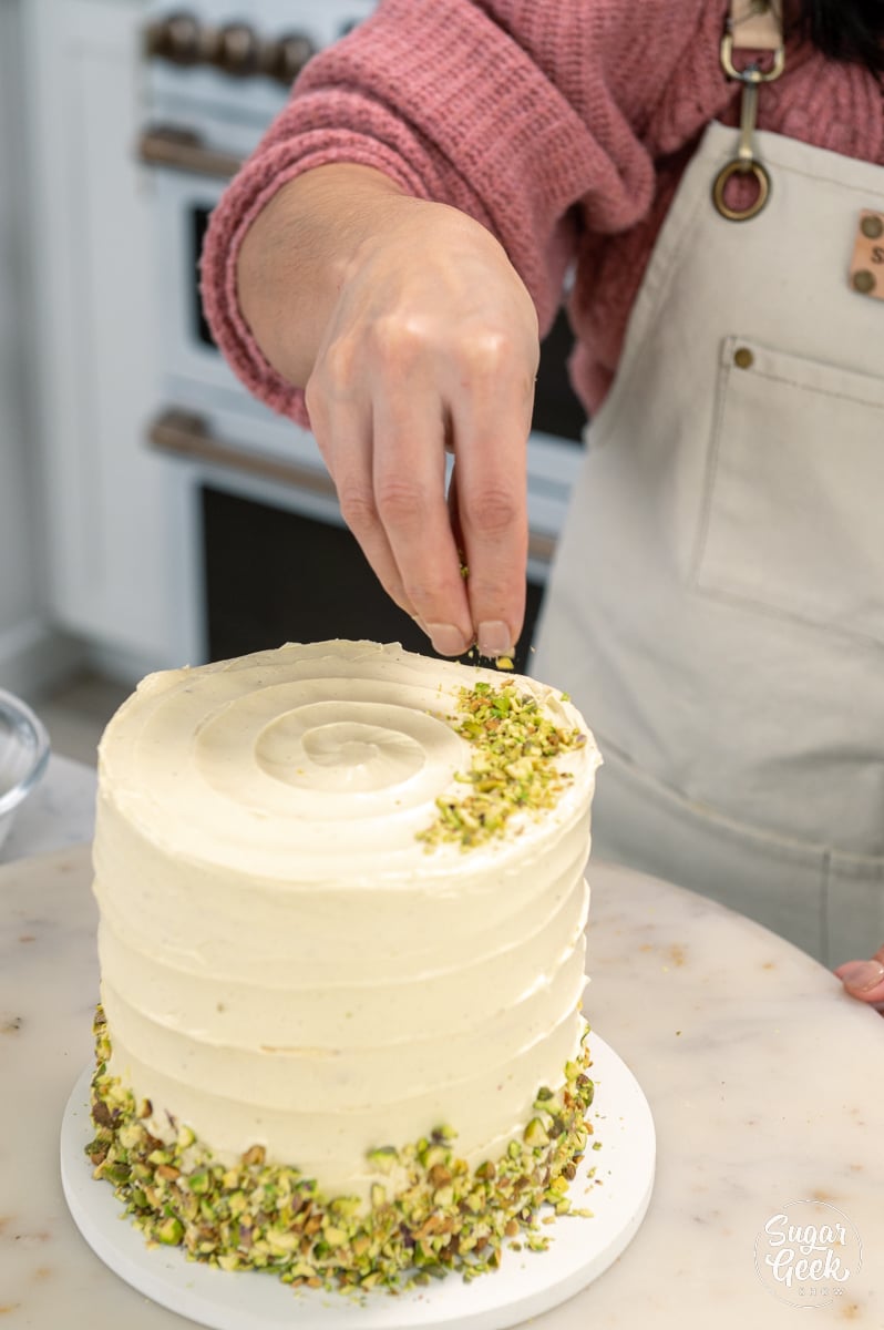 sprinkling pistachios on top of the pistachio cake