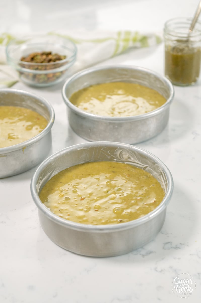 pistachio cake batter divided into cake pans
