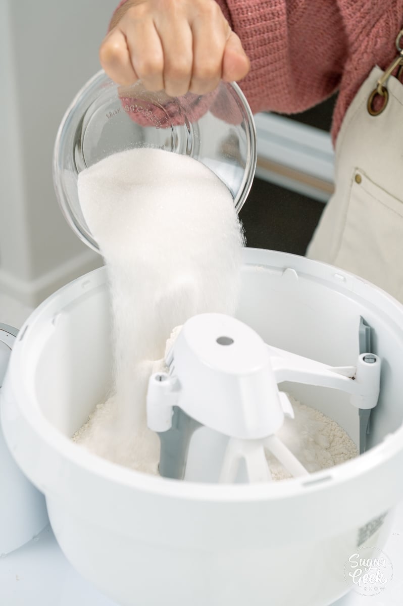 adding dry ingredients to the bowl of a stand mixer
