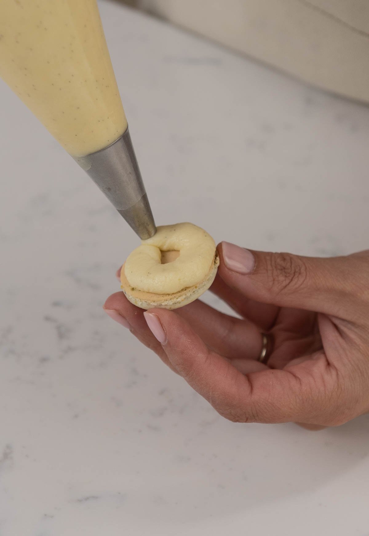 hand piping filling onto a macaron