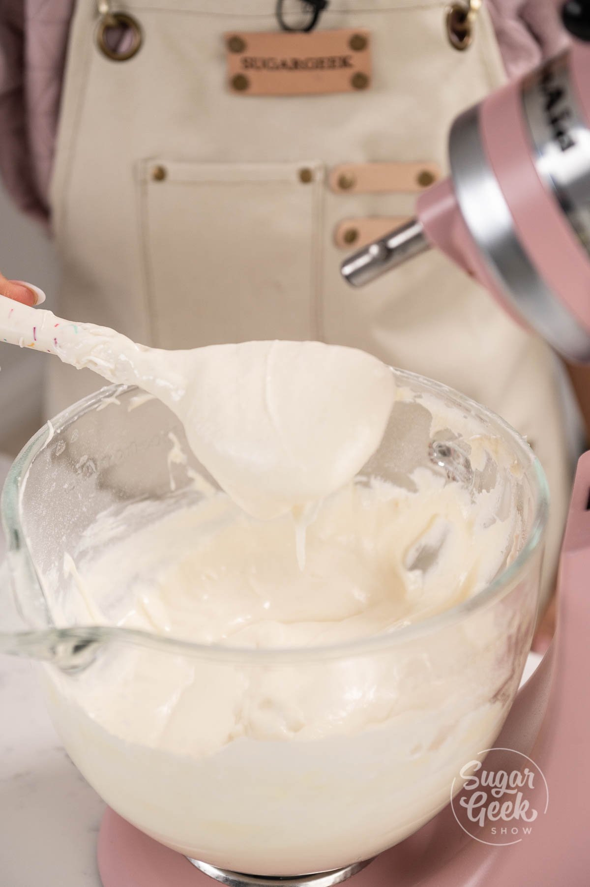 spatula being held above mixing bowl covered in cake batter.