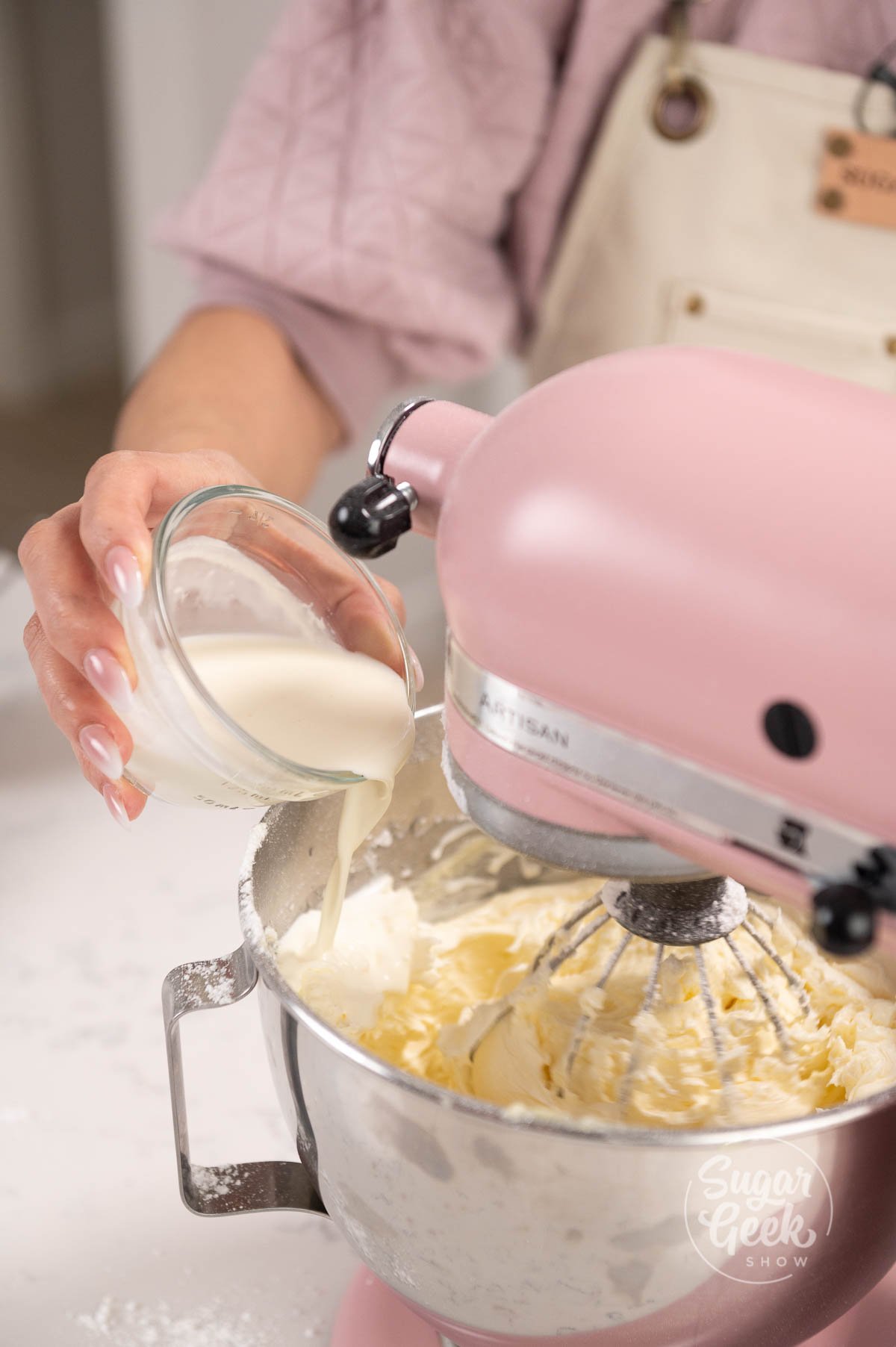 hand pouring bowl of cream into a mixer