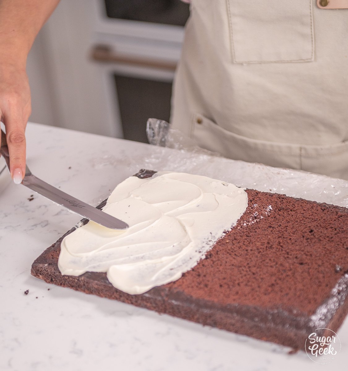 smoothing buttercream on top of chocolate cake