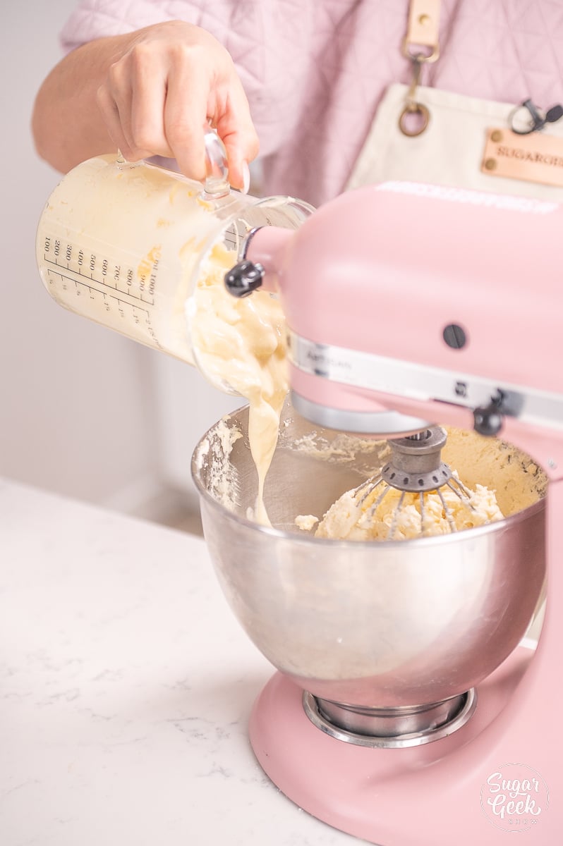 pouring warm buttercream into mixing bowl