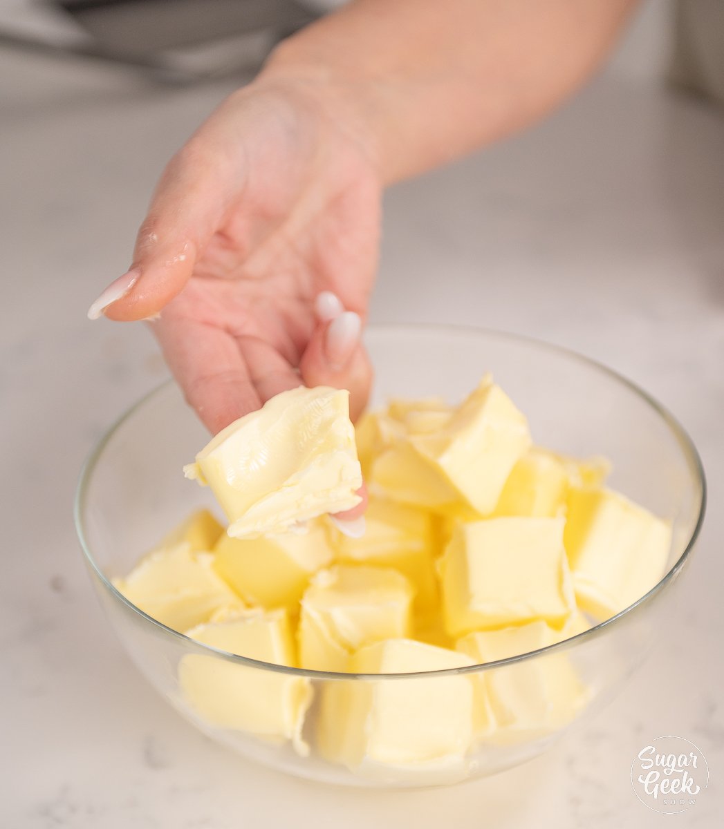 hand holding a piece of butter showing it's soft