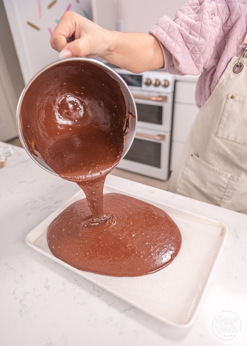 pouring cake batter into a baking sheet