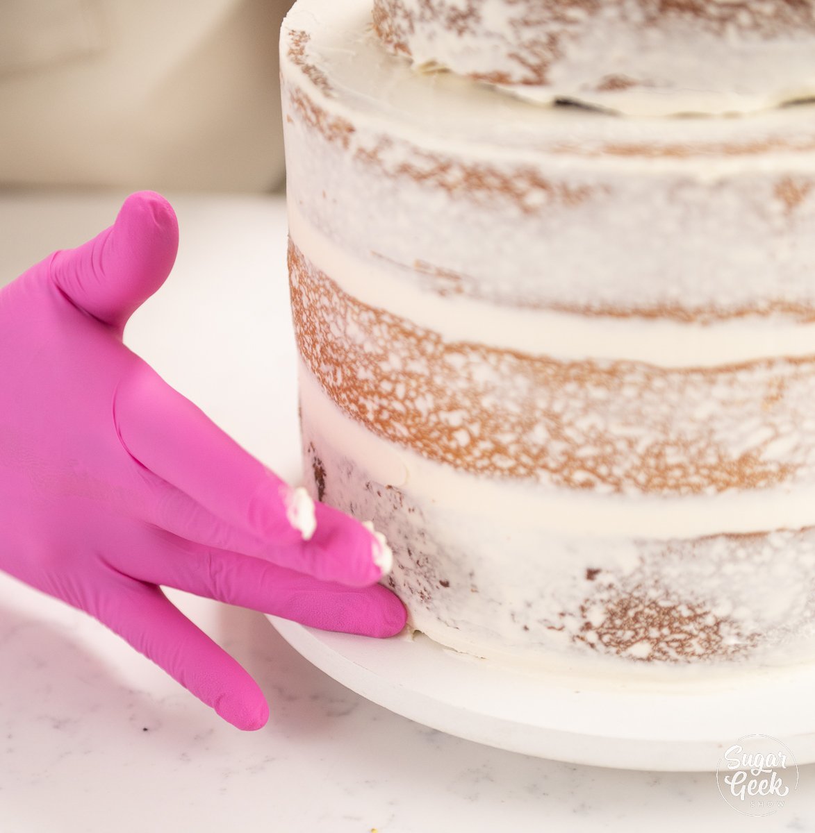 hand smoothing buttercream on cake