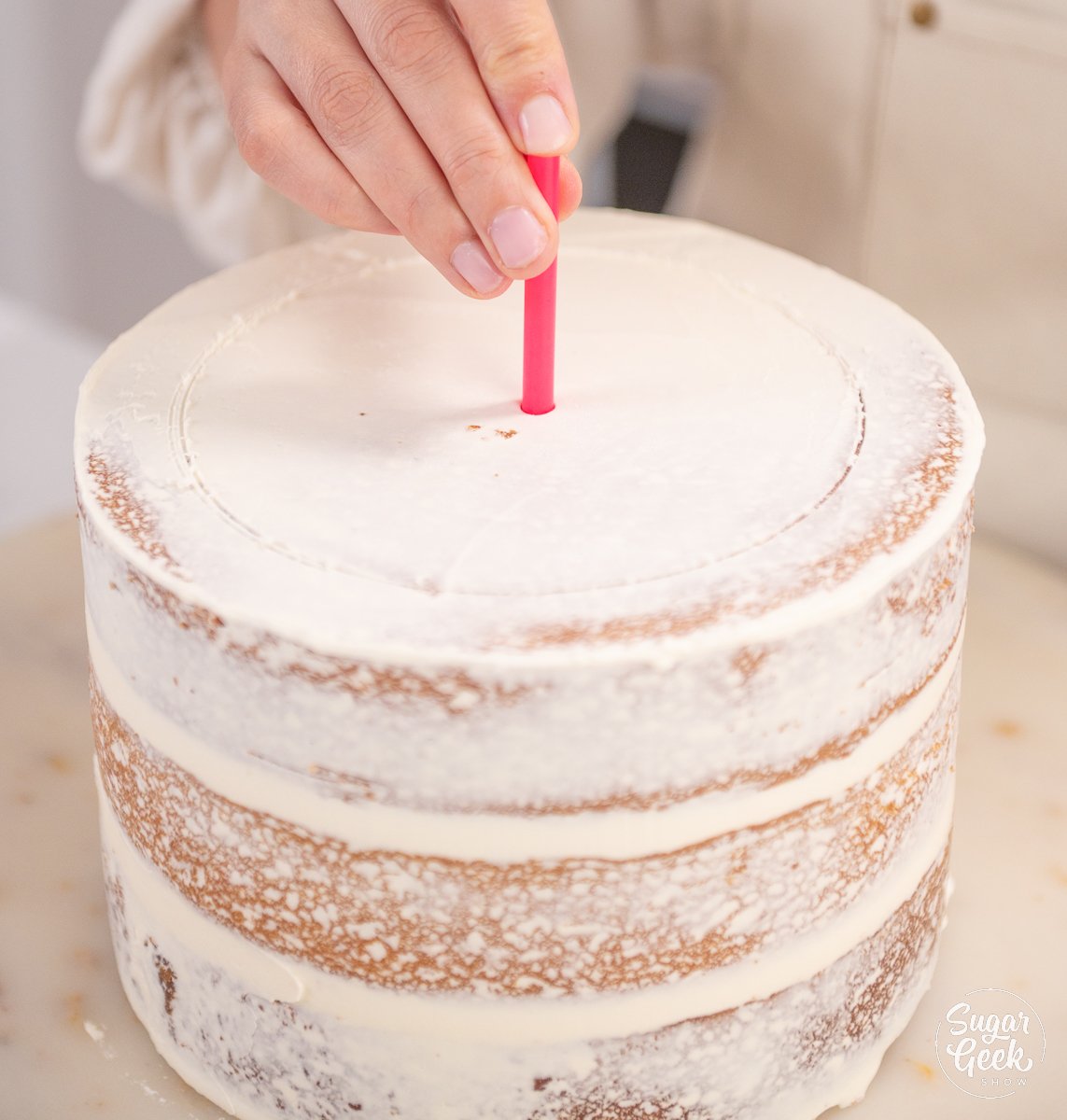 inserting a straw into the center of the top of a cake
