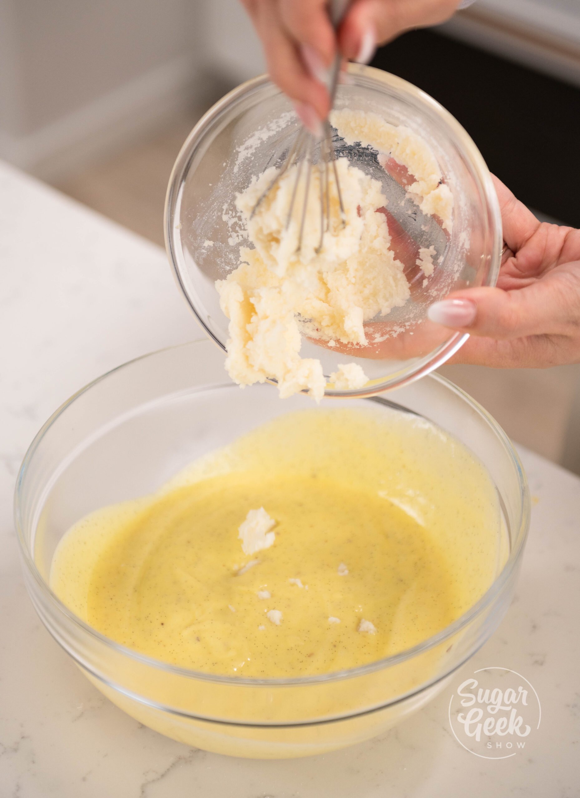 hand pouring bowl of gelatin into bowl of cream