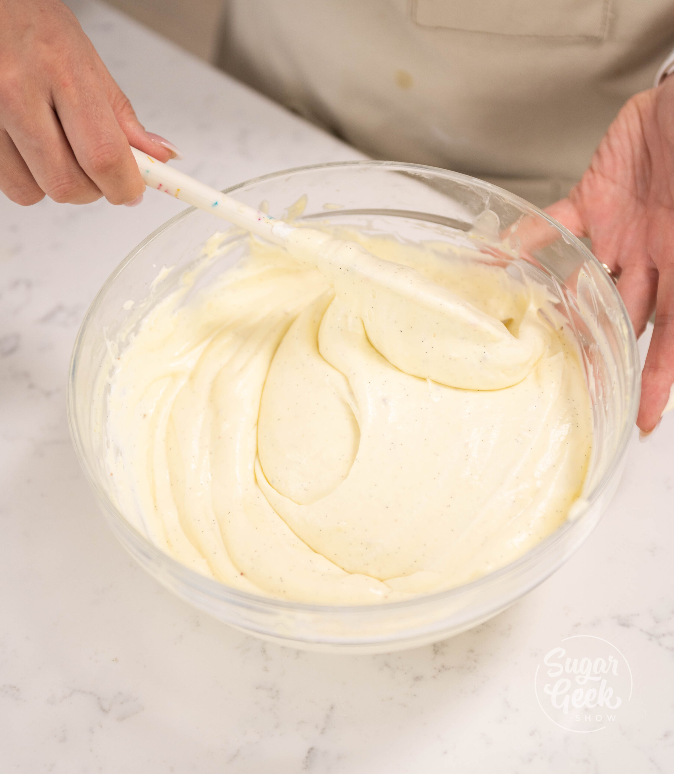 hand holding spatula mixing bowl of bavarian cream