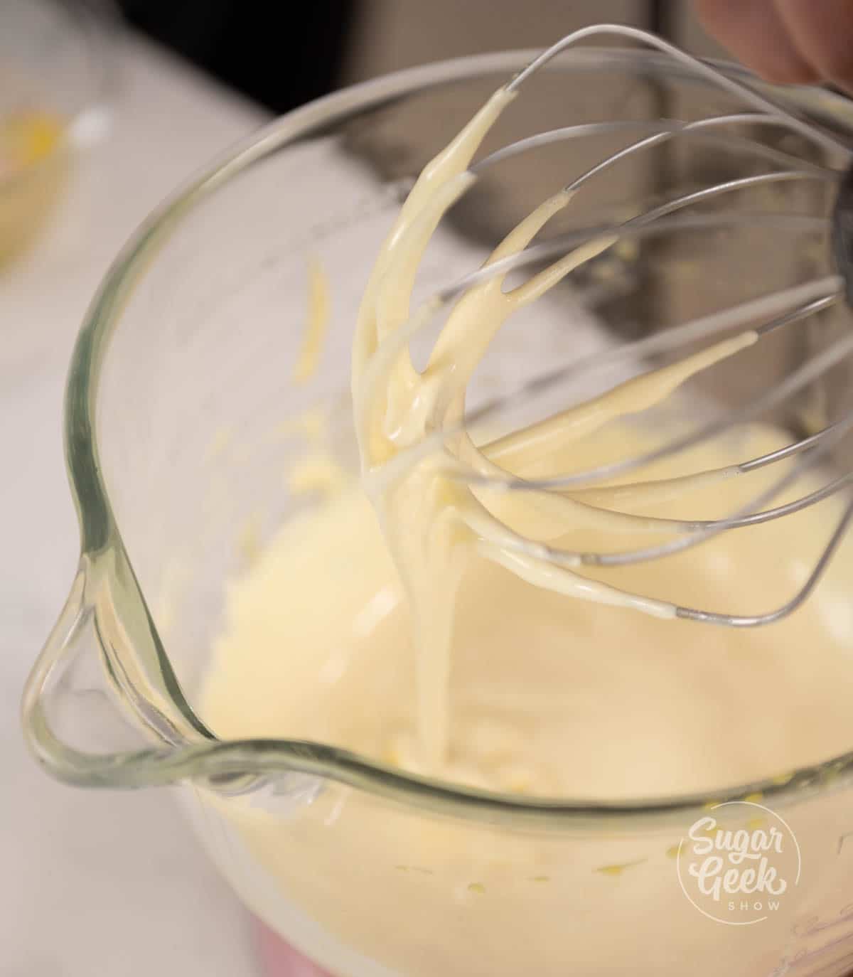 Whisk attachment covered in lady finger batter over mixing bowl