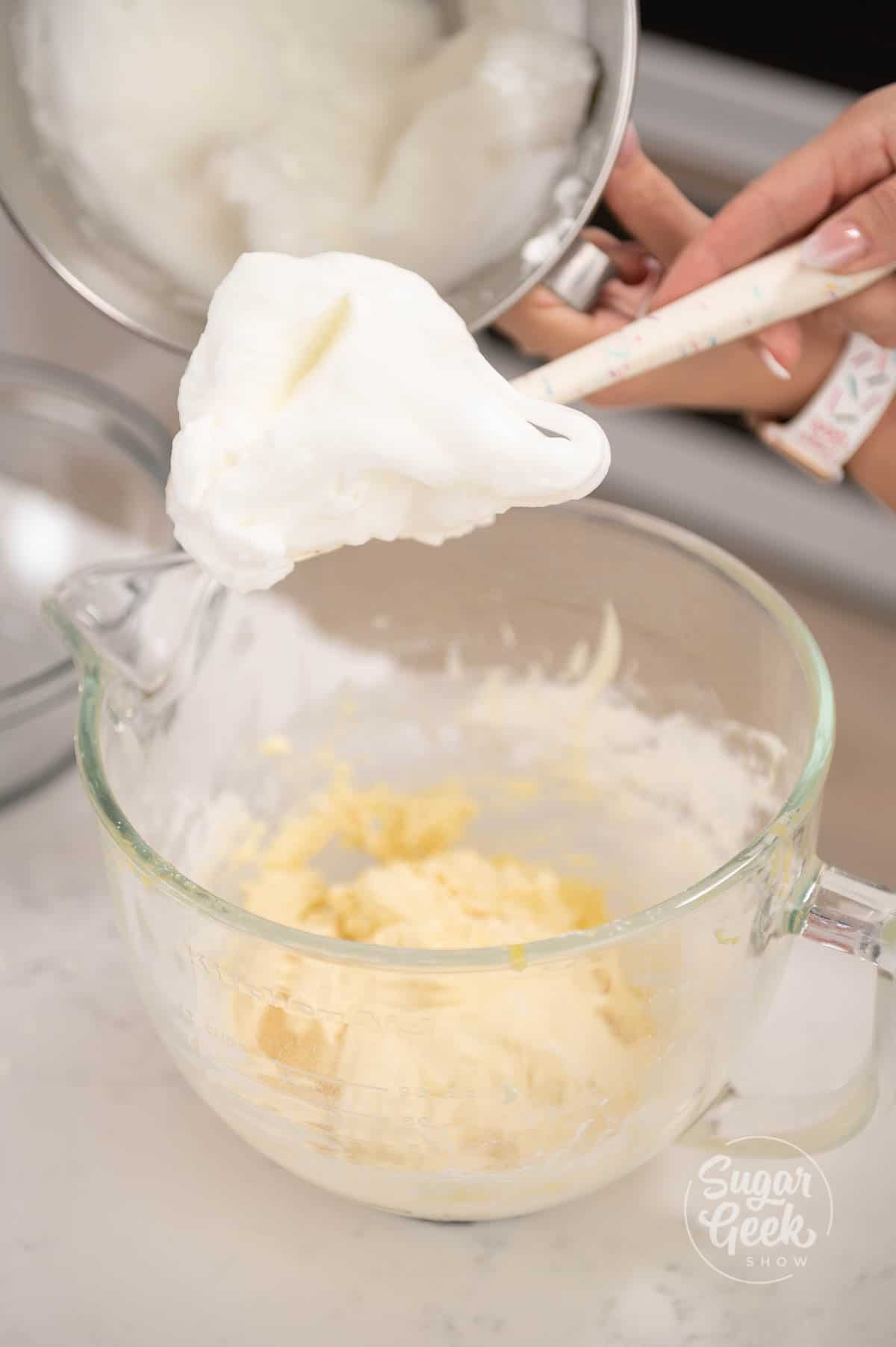 hand holding spatula covered in batter over mixing bowl