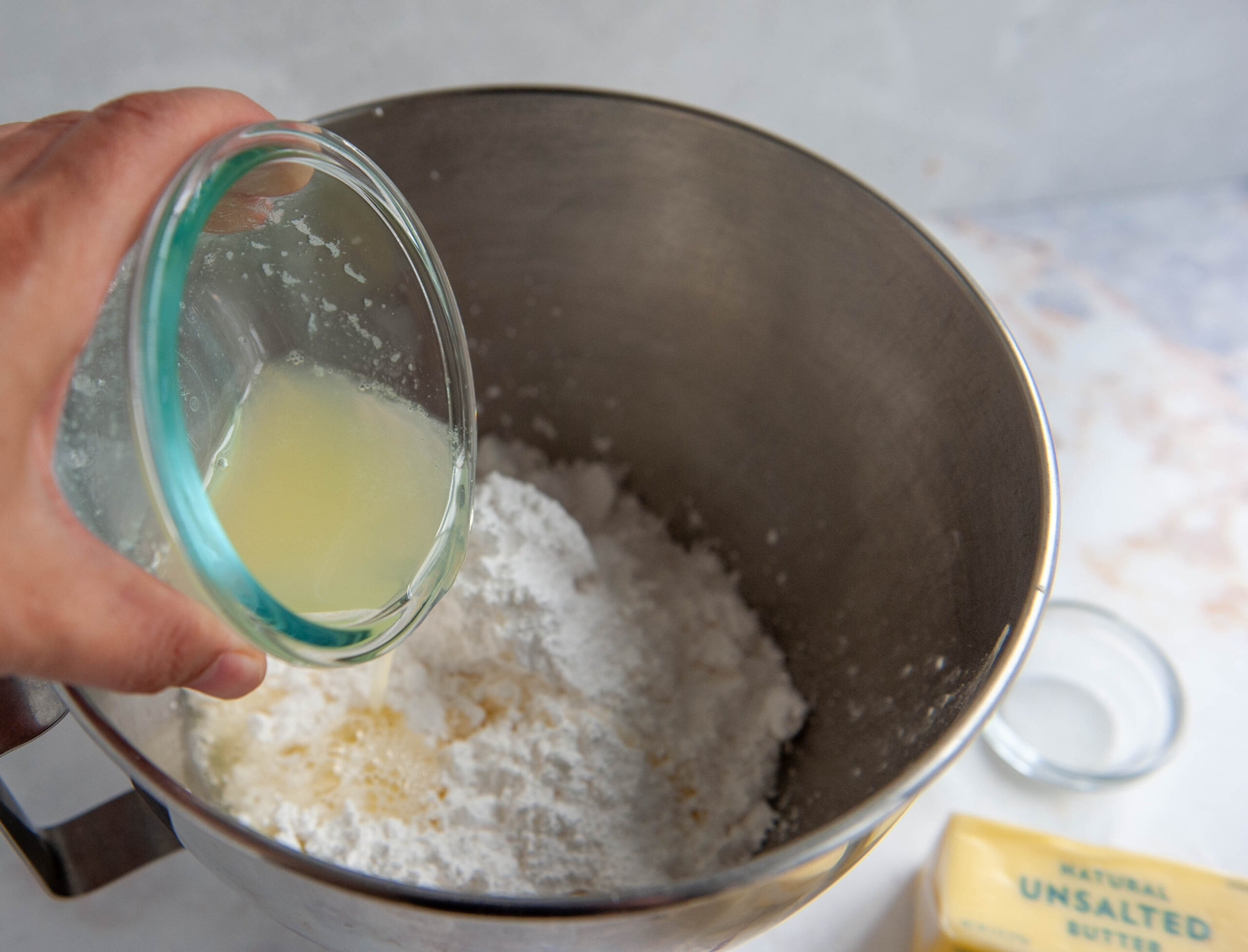 hand pouring egg whites into bowl of stand mixer