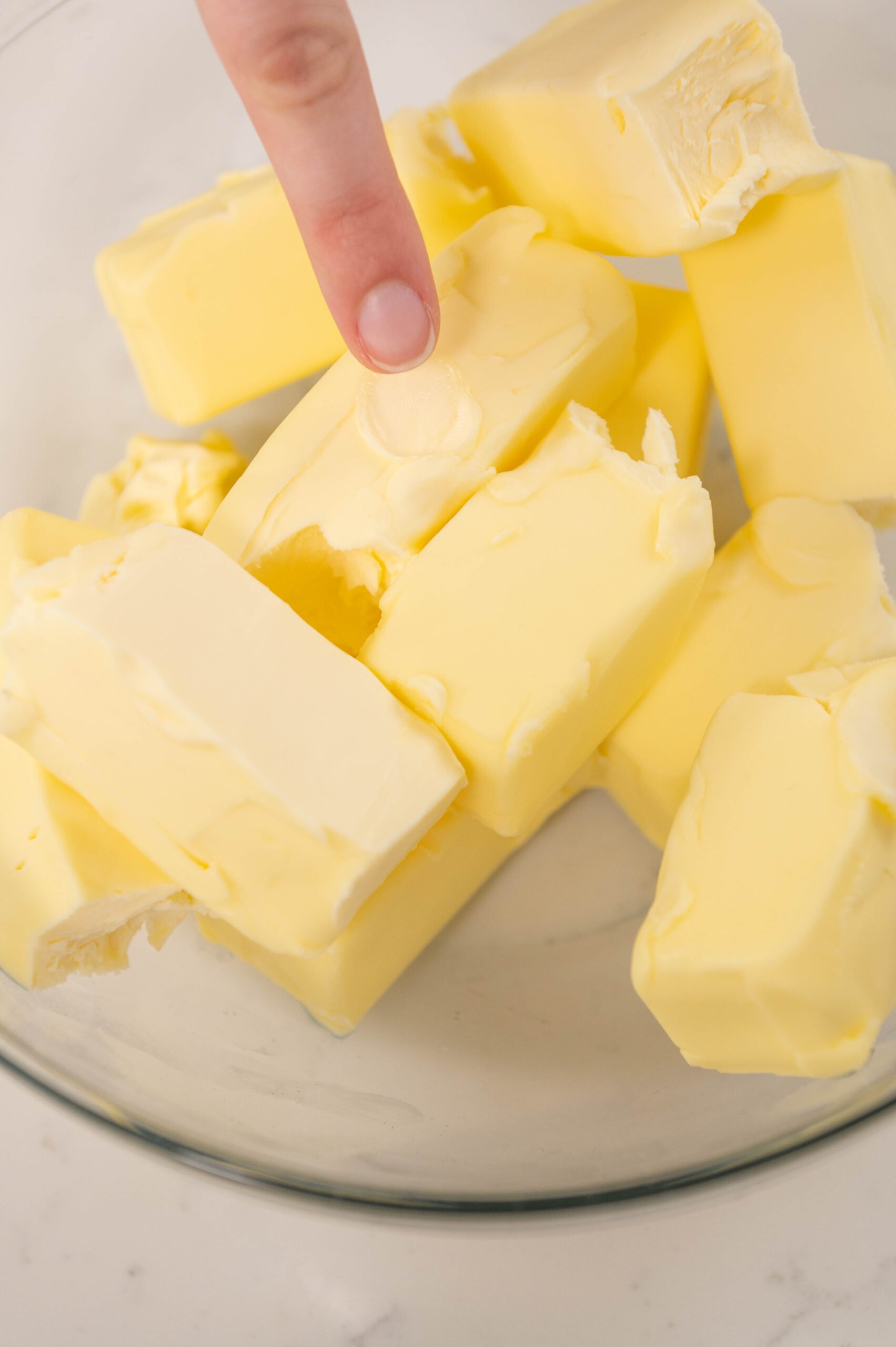 finger pressing an indent into butter