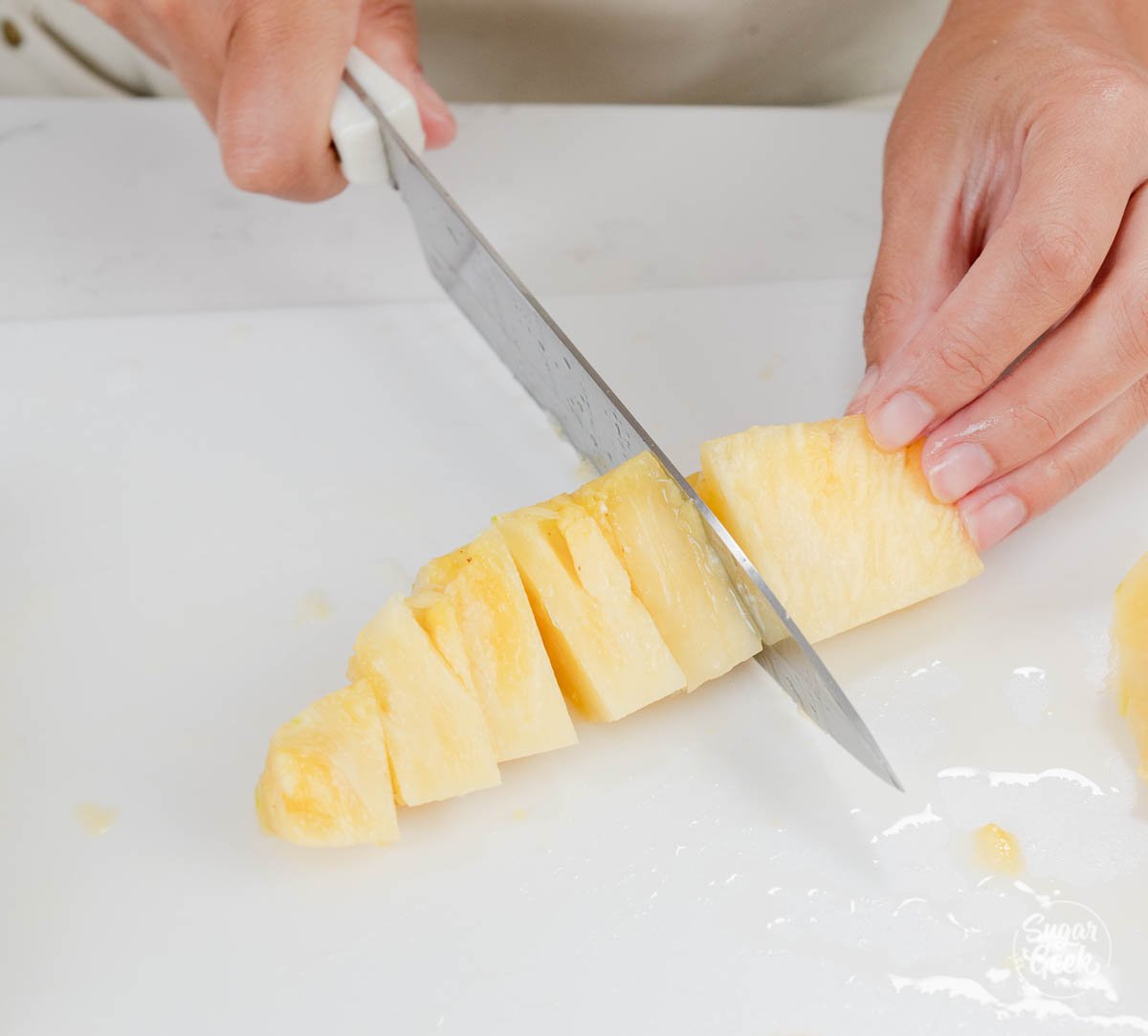 hand using knife to dice pineapple.