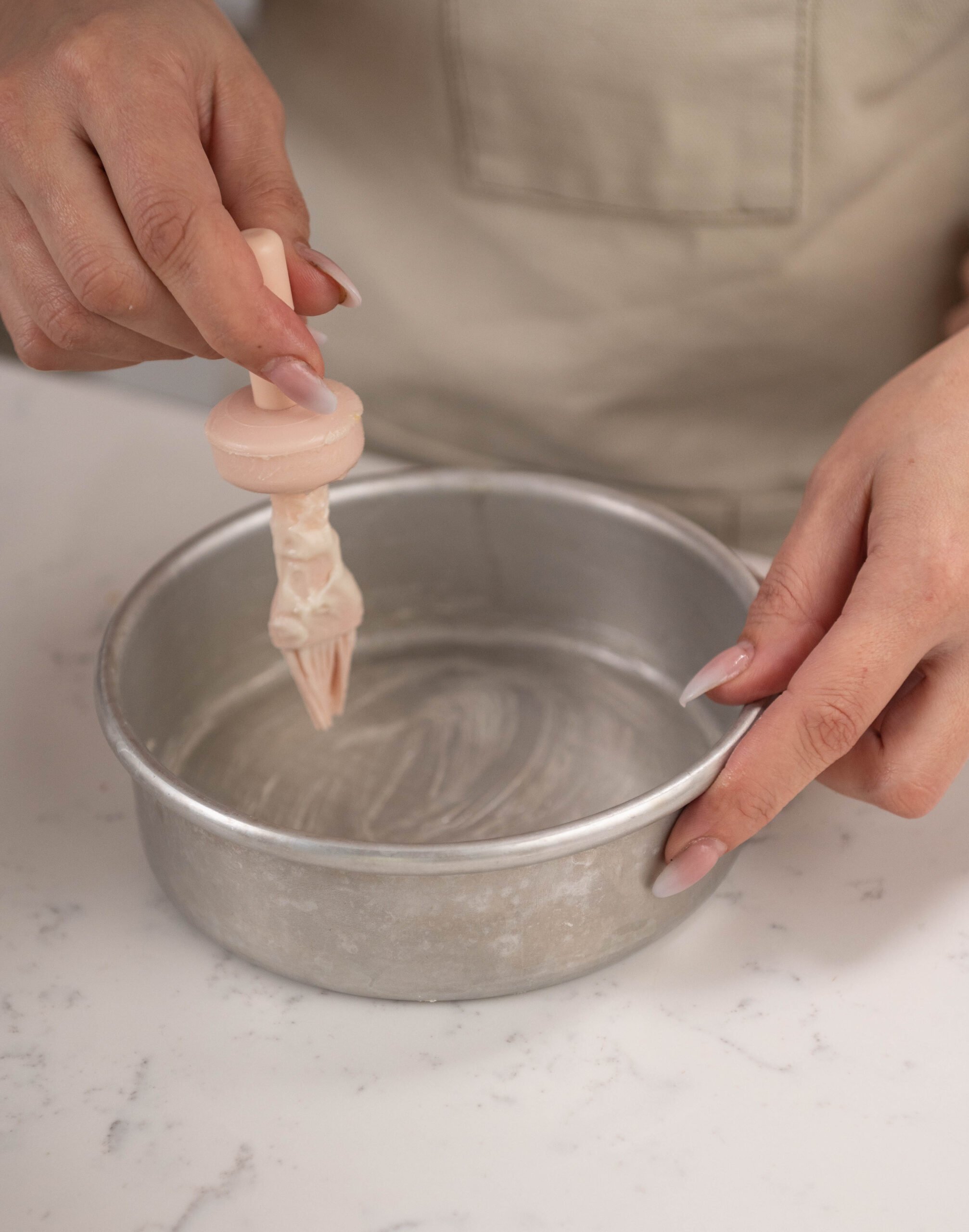 hand holding bursh painting pan release on cake pan