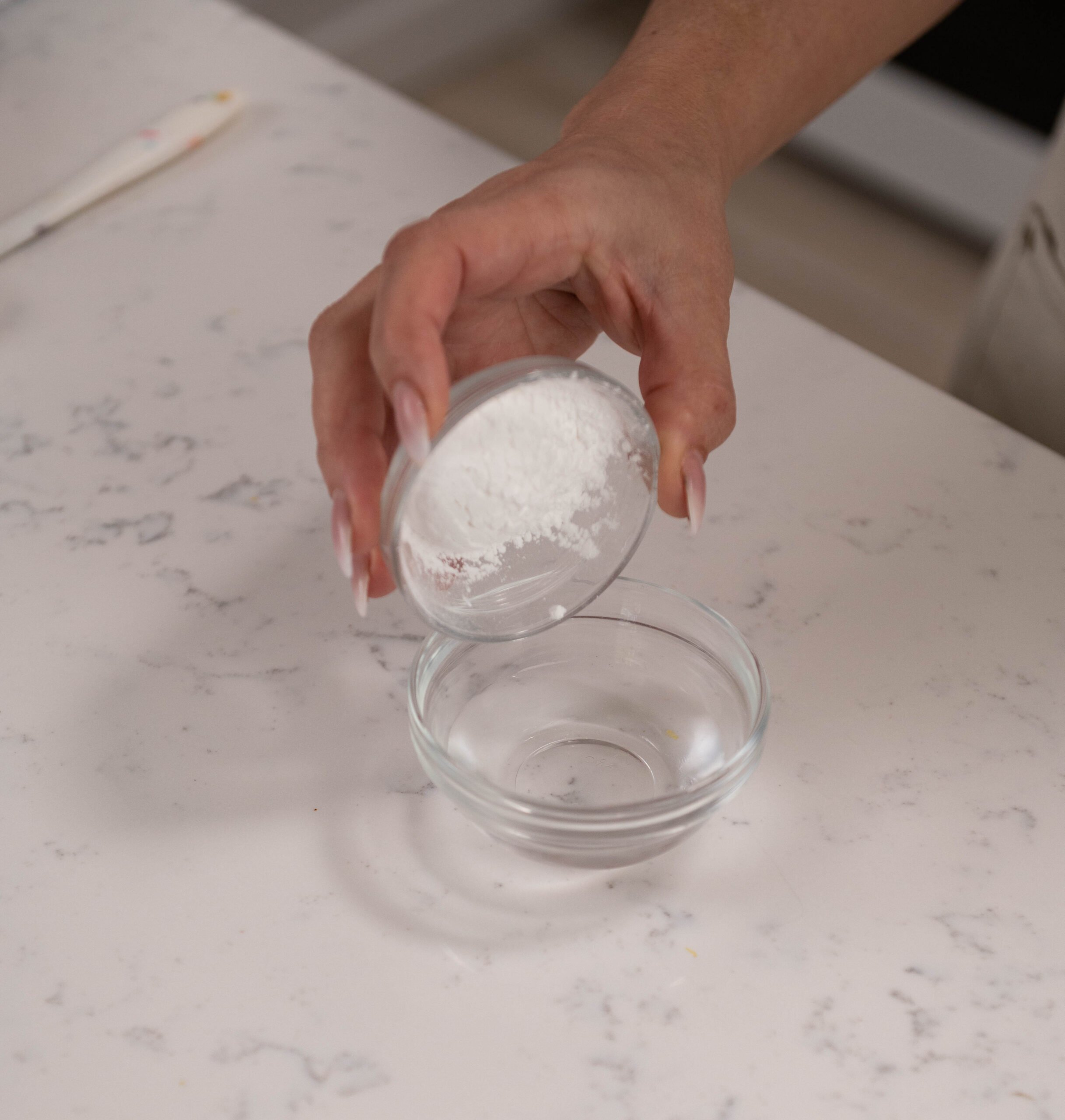 hand pouring bowl of cornstarch into bowl of water