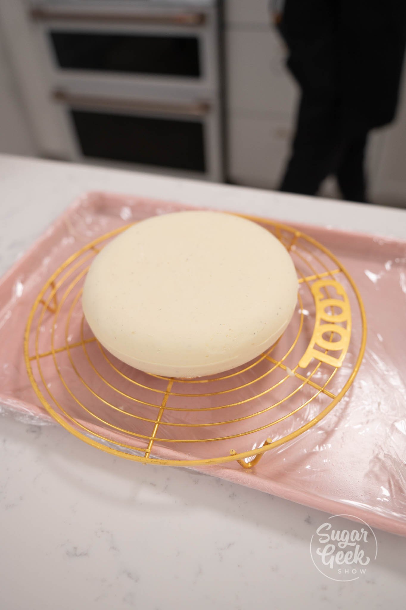 frozen entremet sitting on a cooling rack to be glazed.