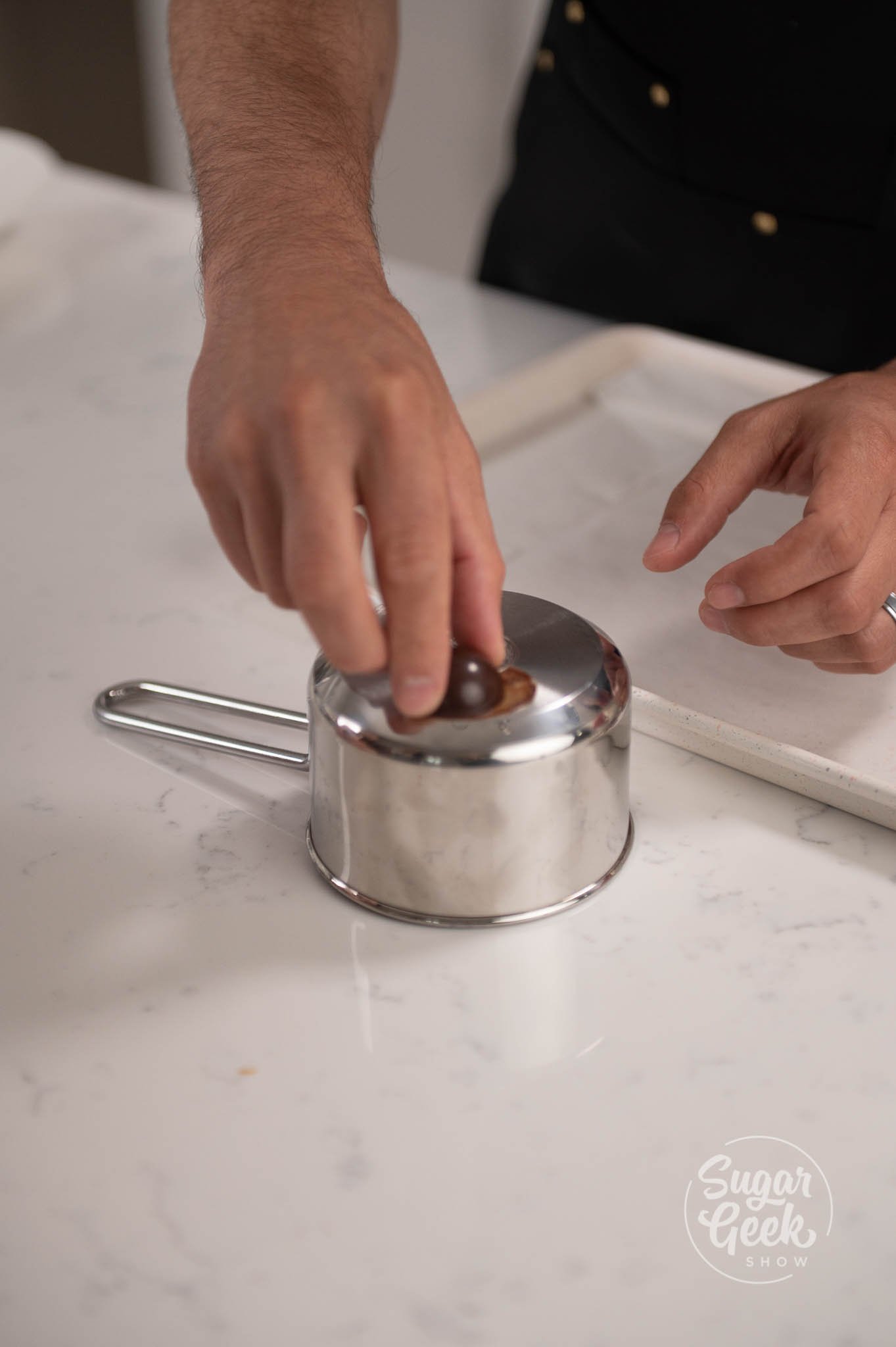 hand using warm pot to melt bottom of chocolate.