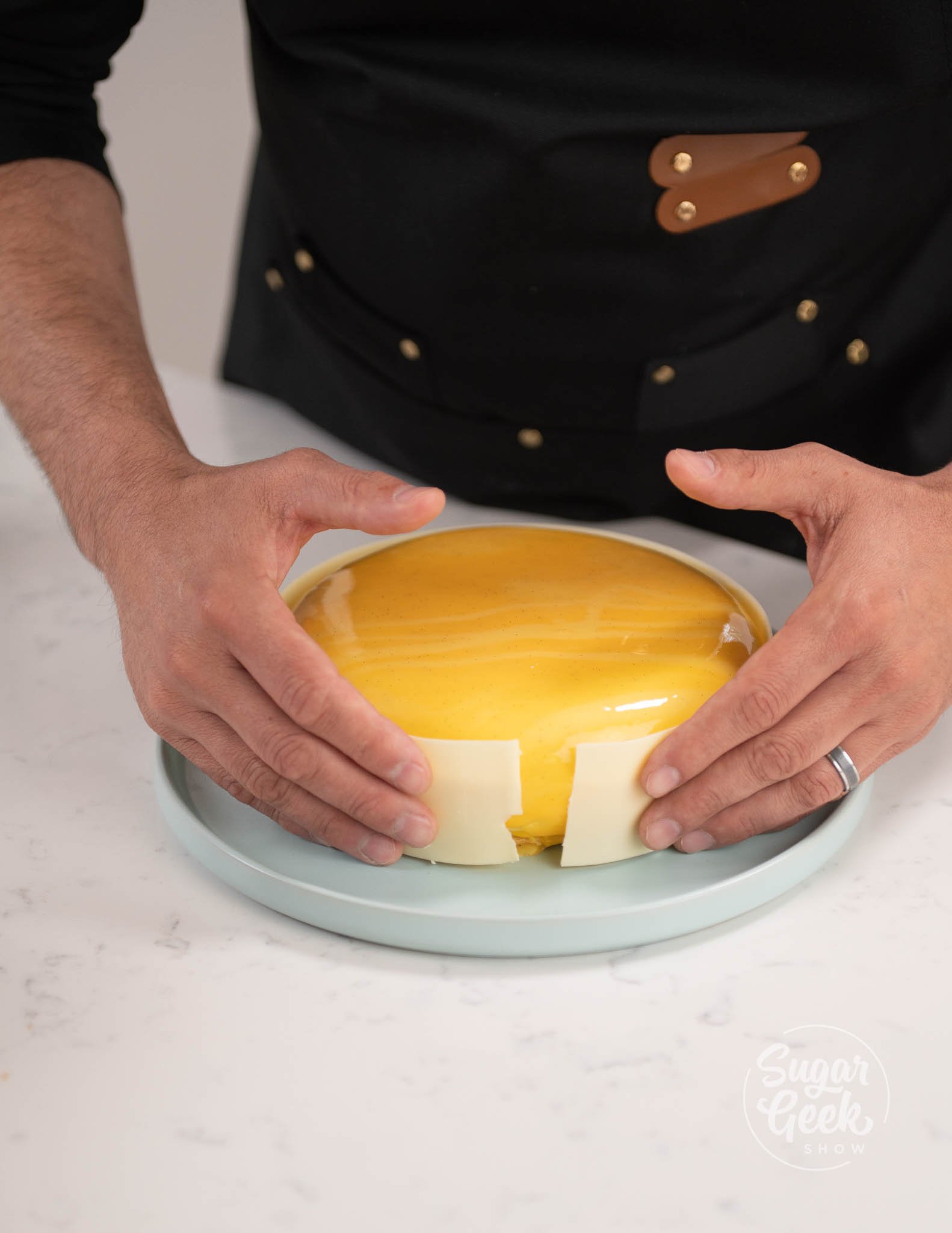 hands placing chocolate ring around entremet.