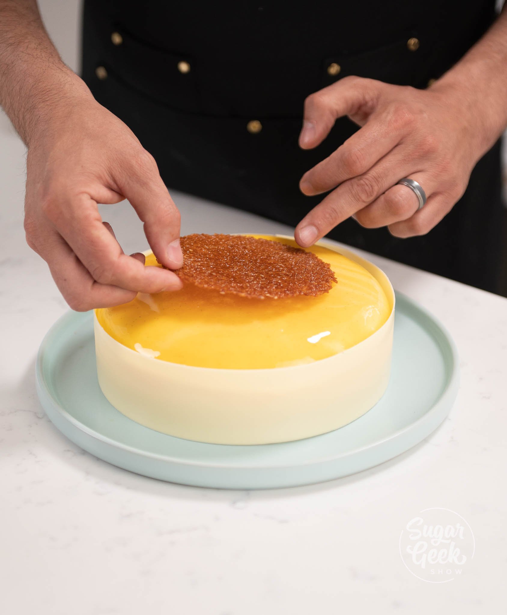 hands placing disc of nougatine on top of entremet.