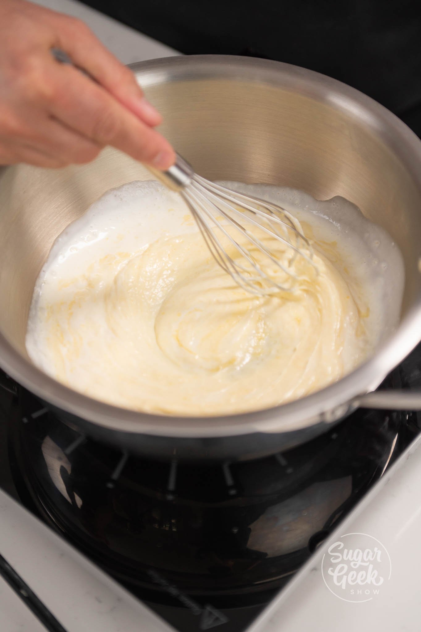 hand whisking mixture in pan with a hand whisk