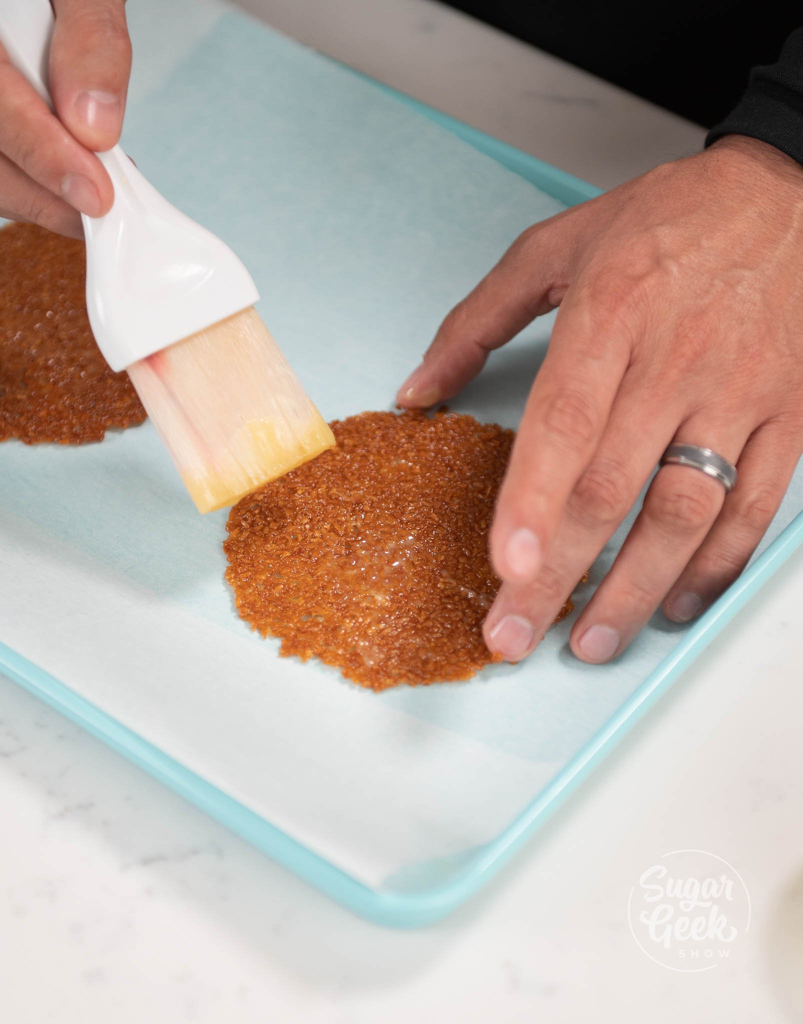 hand using pastry brush to brush cocoa butter onto nougatine.