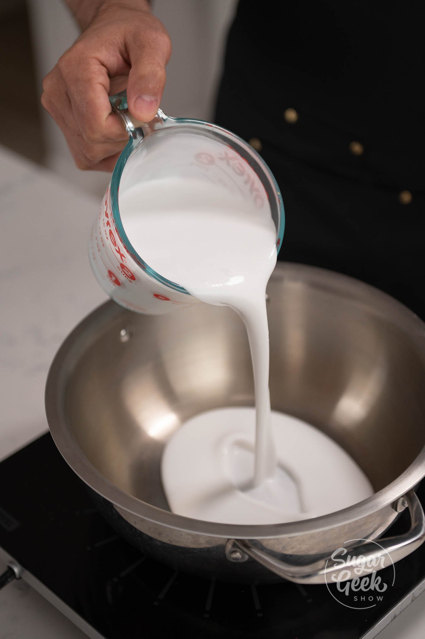 hand pouring measurement of cream into pot.