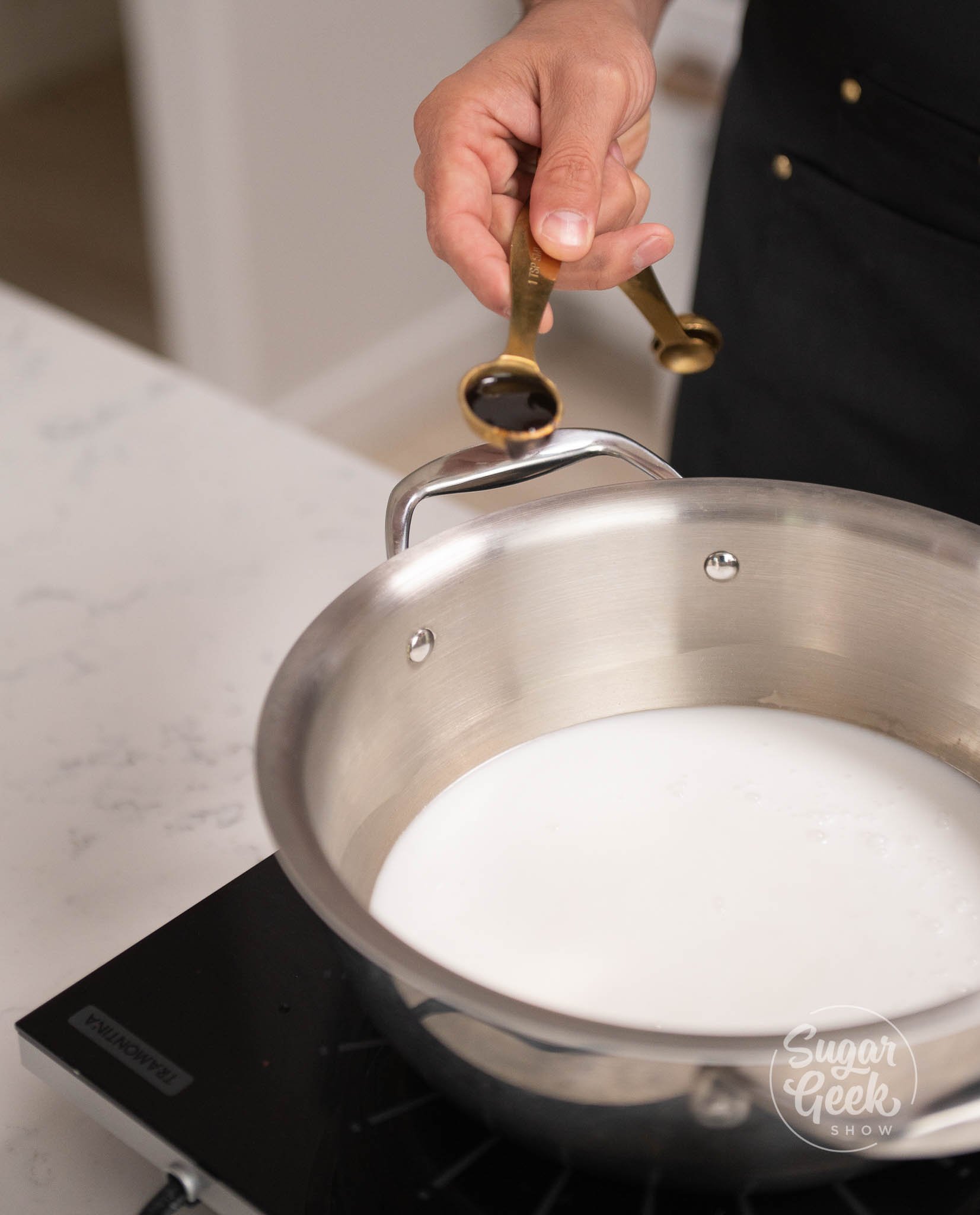 hand adding measurement of vanilla into pot.