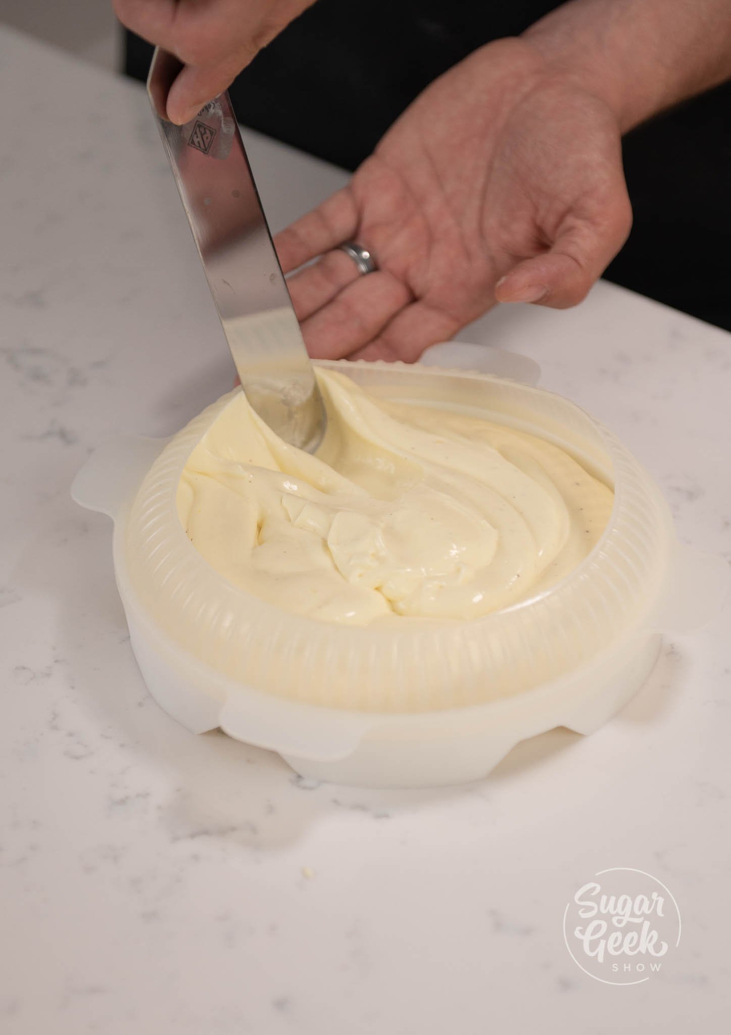 hand using knife to spread mousse around the mold.