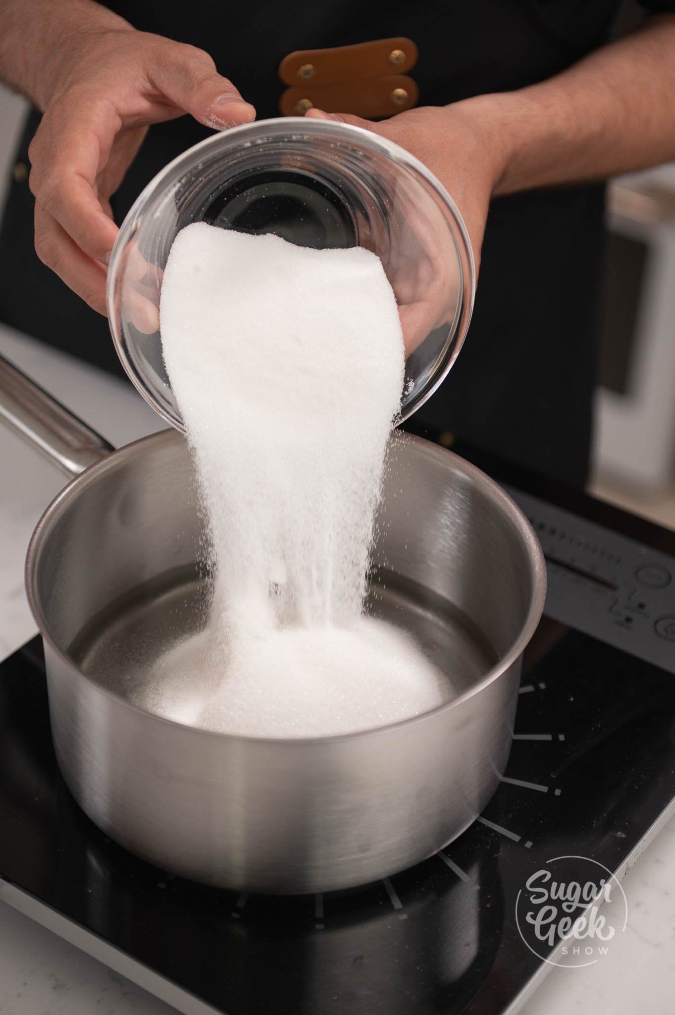 hand pouring container of sugar into pot.