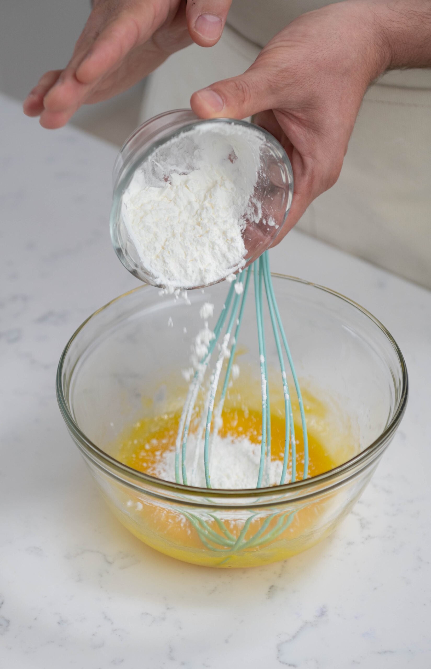 hands adding cornstarch into mixing bowl.
