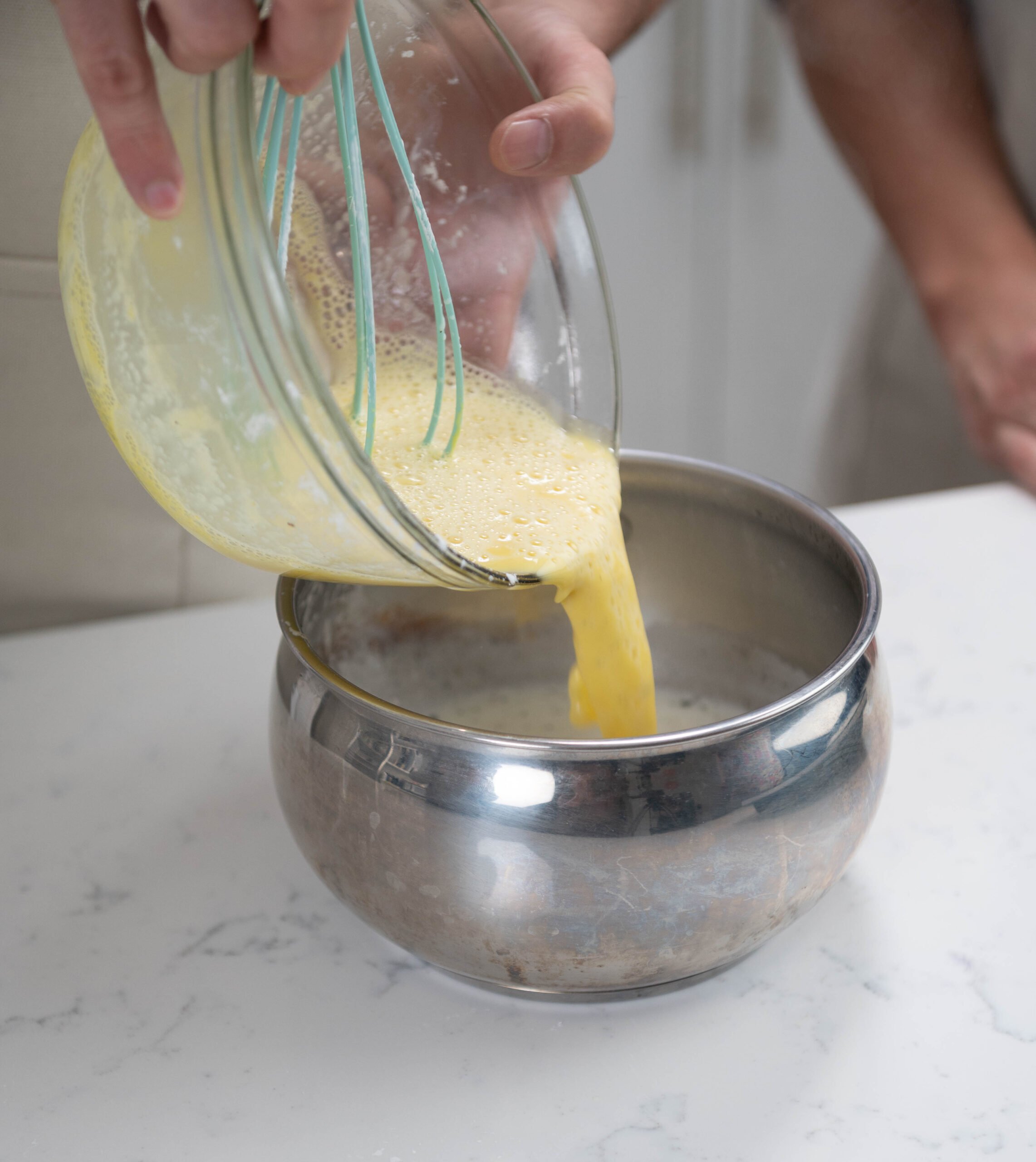 hands pouring yolks into pot.
