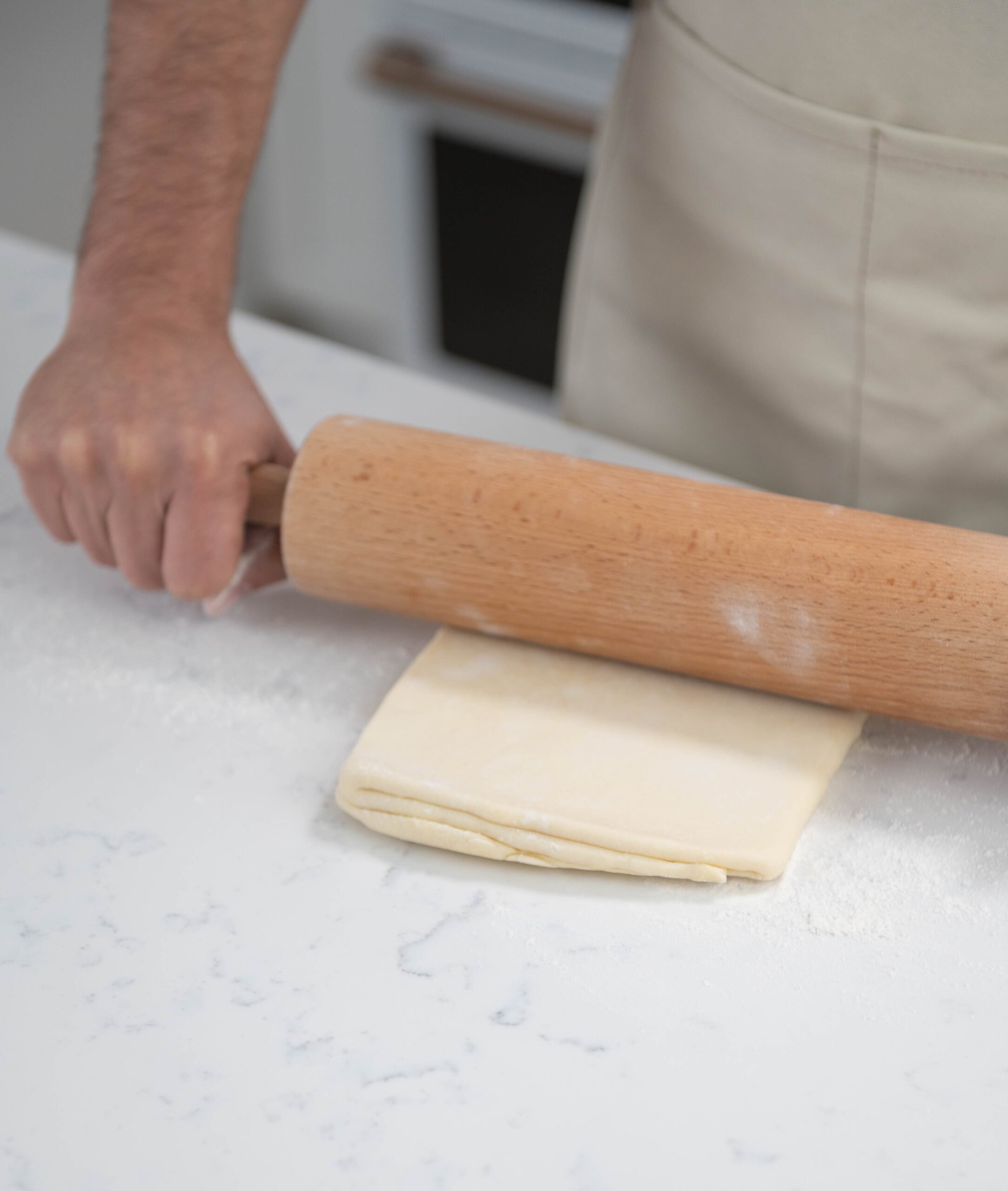 hands rolling dough with rolling pin.