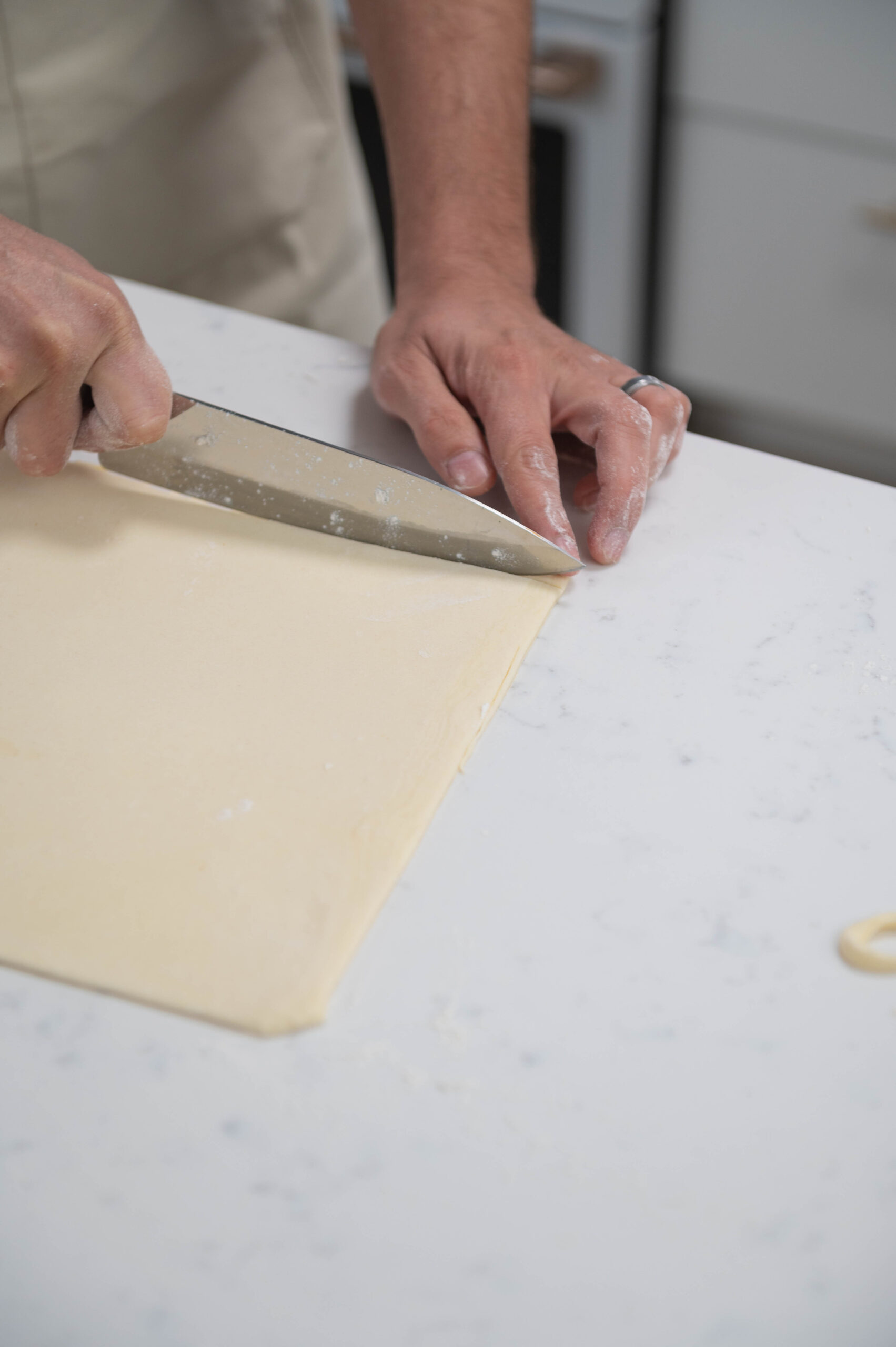 hands using knife to trim dough.