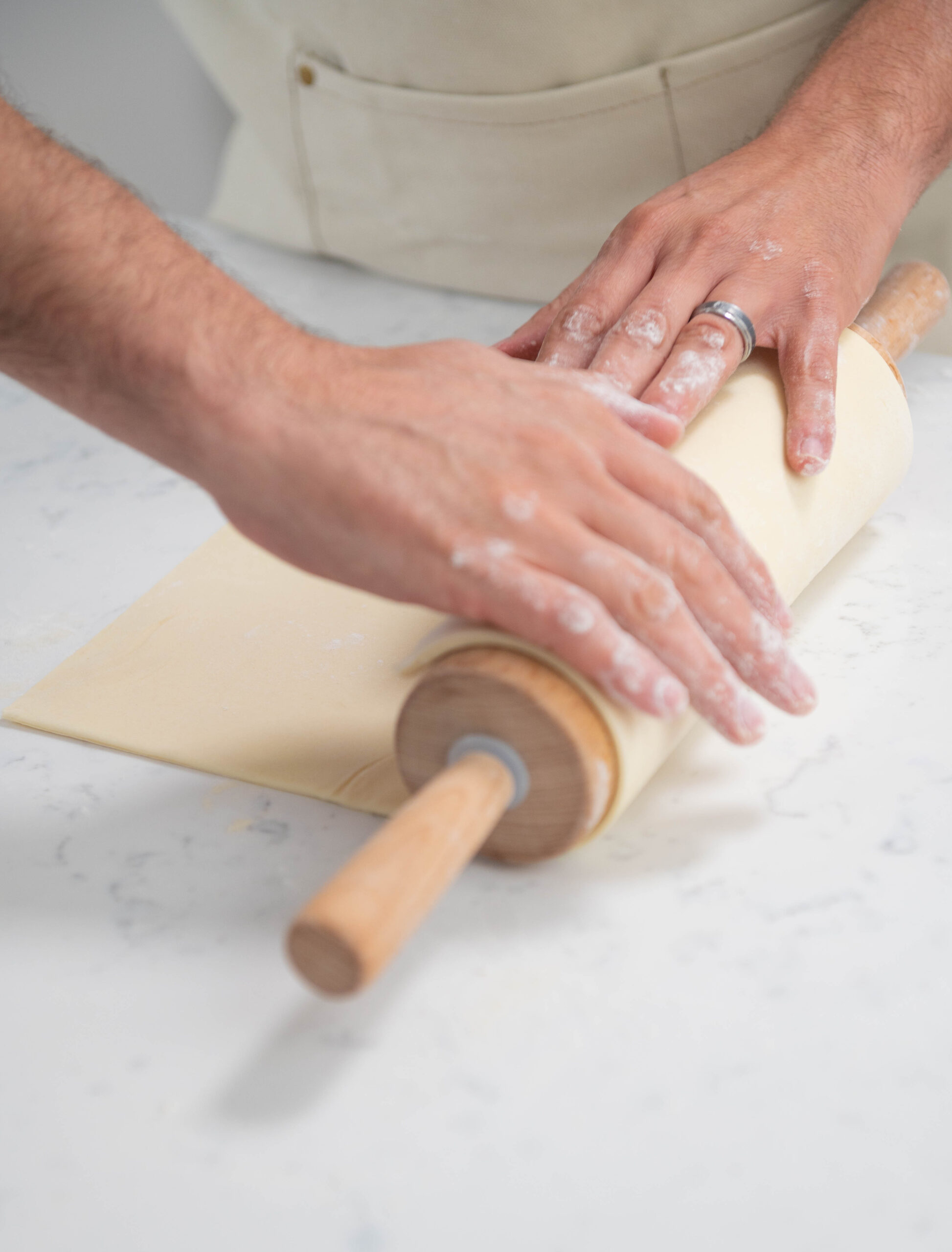 hands using rolling pin to roll dough.