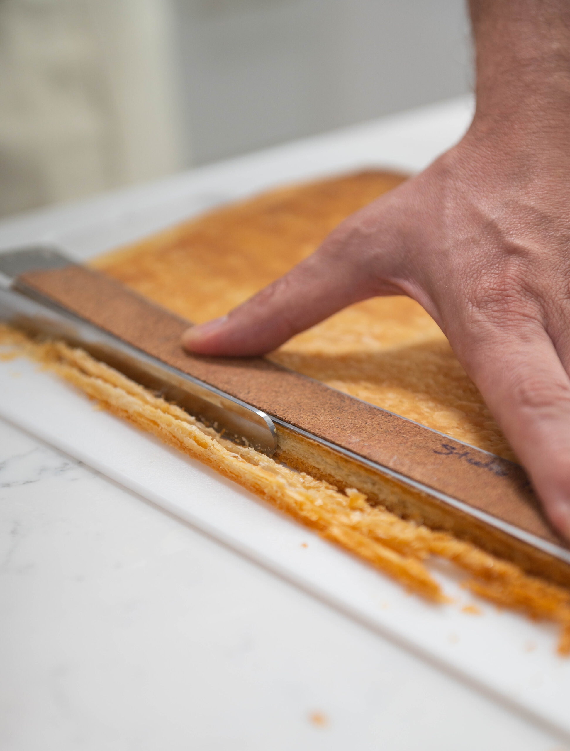 hand using knife to trim the edges of puff pastry.