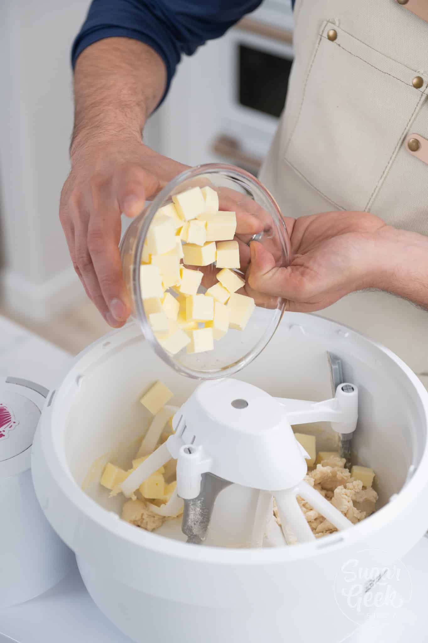 adding cold butter cubes to the bowl of a stand mixer. 