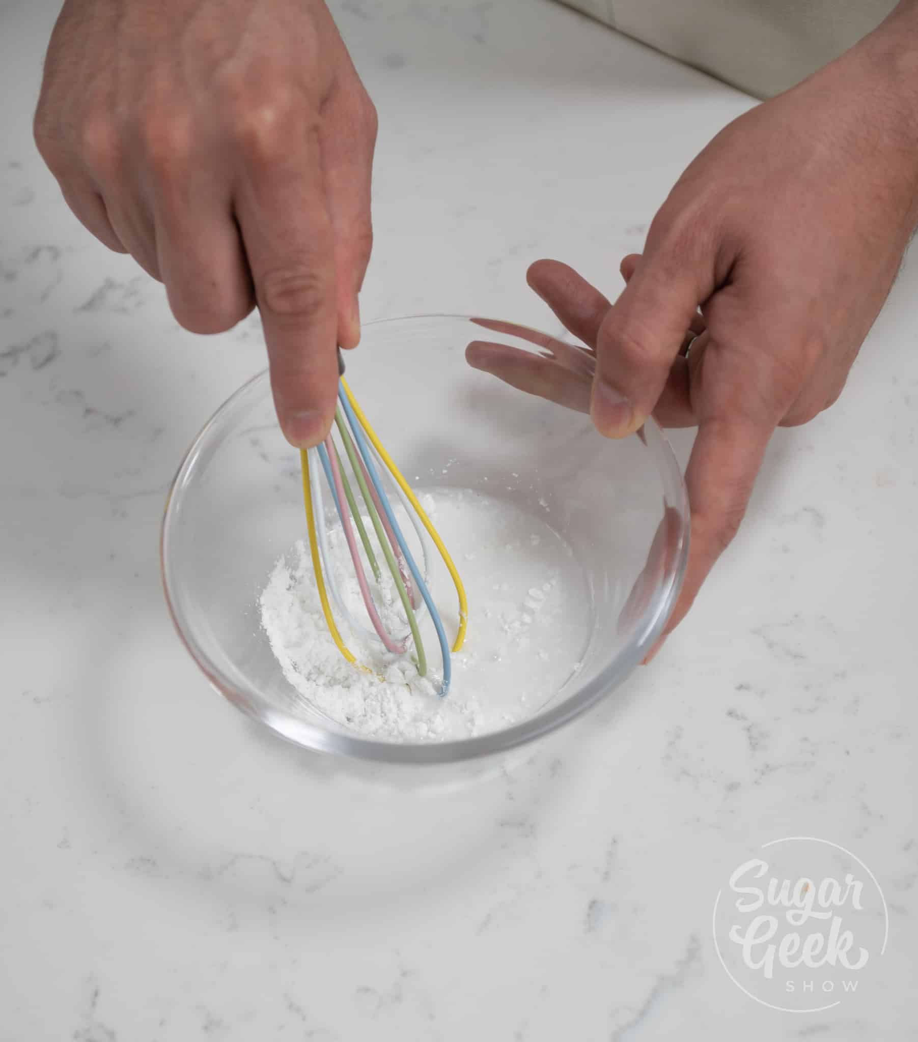 hand using whisk to whisk together cornstarch and water.