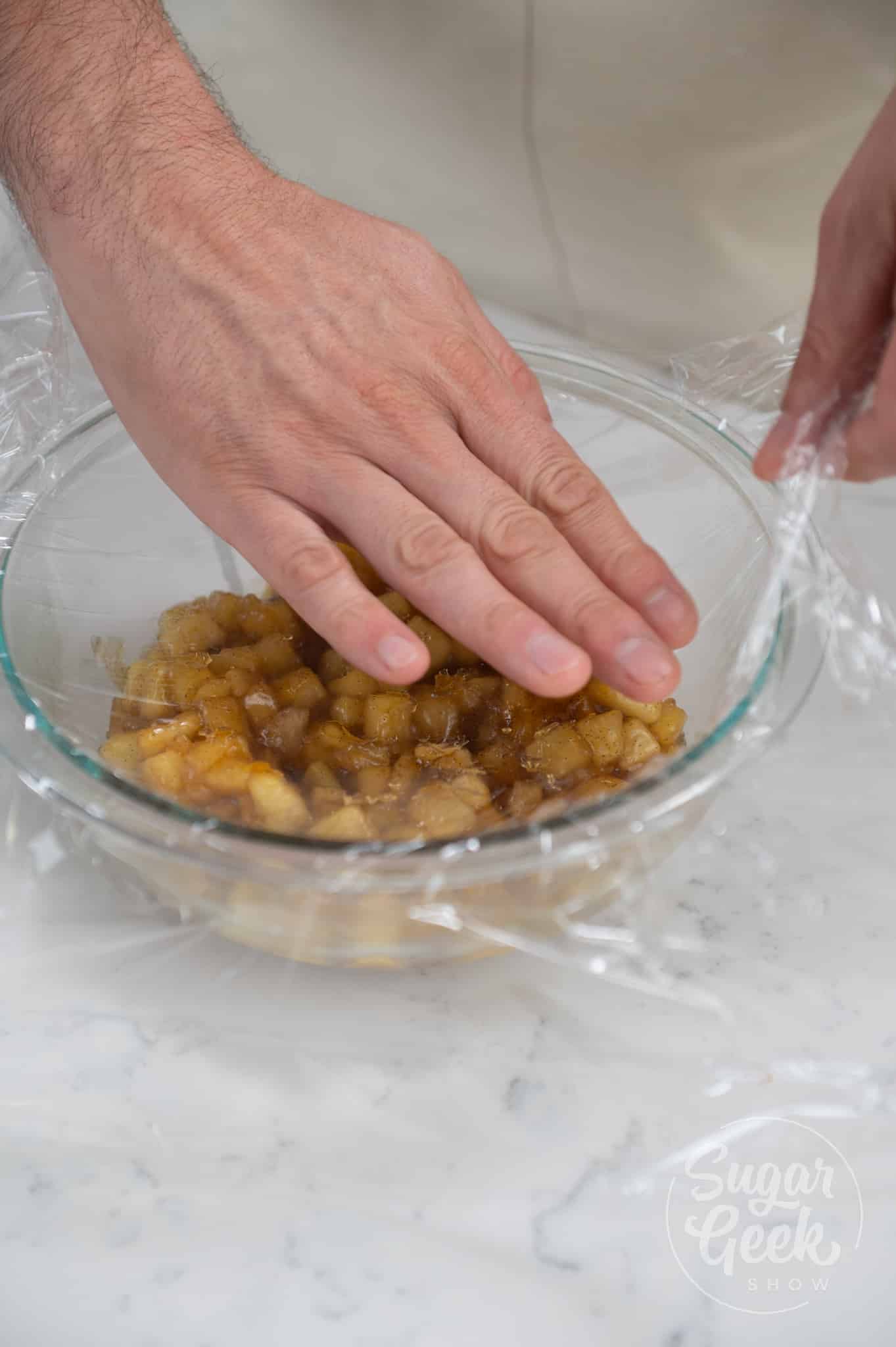 hand placing plastic wrap on top of filling.