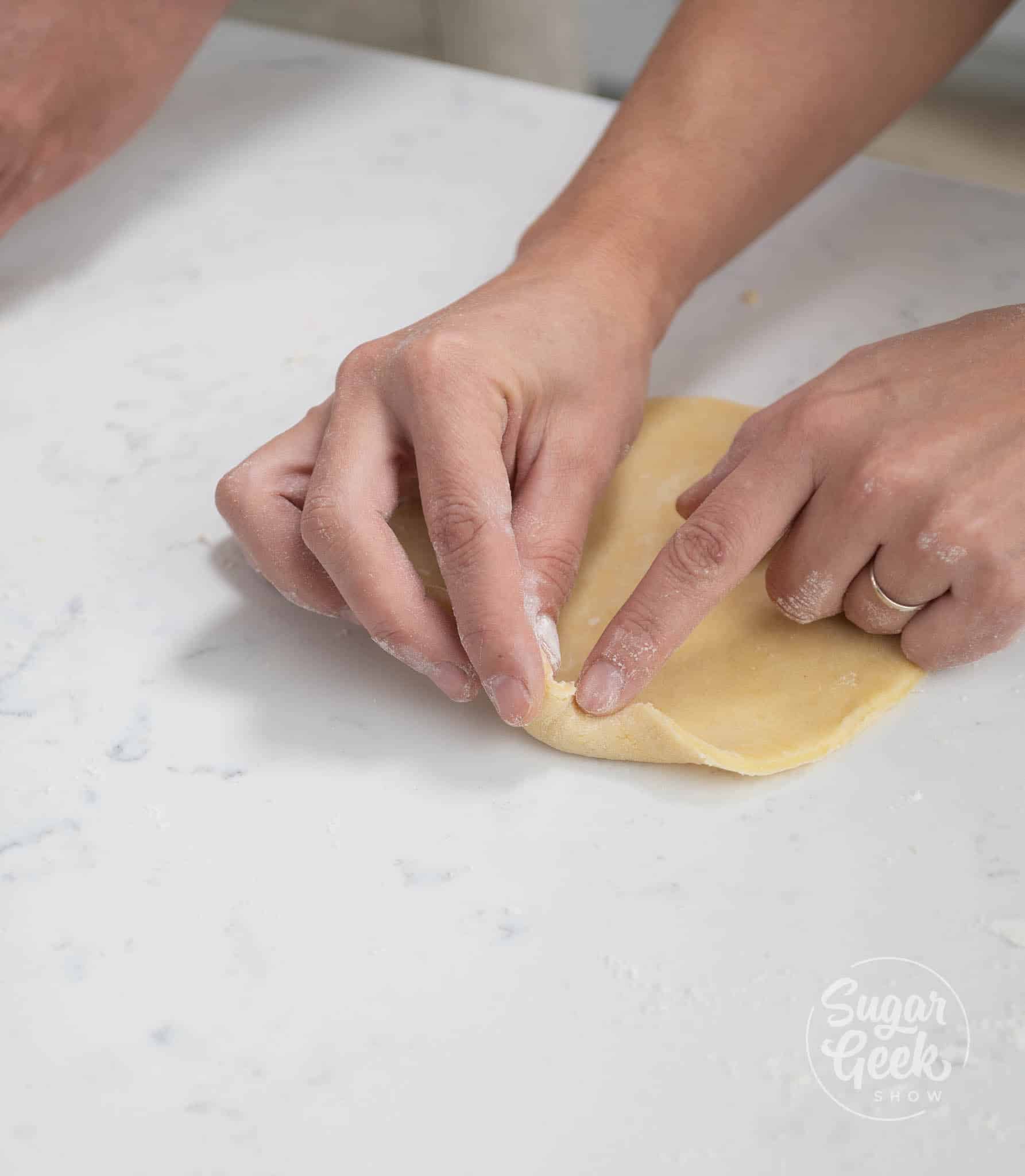 hands using fingers to form edges on to the dough