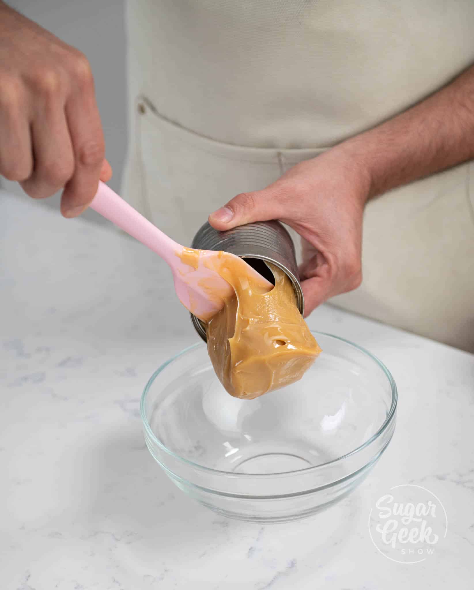 hand using spatula to scrape dolce de leche from can