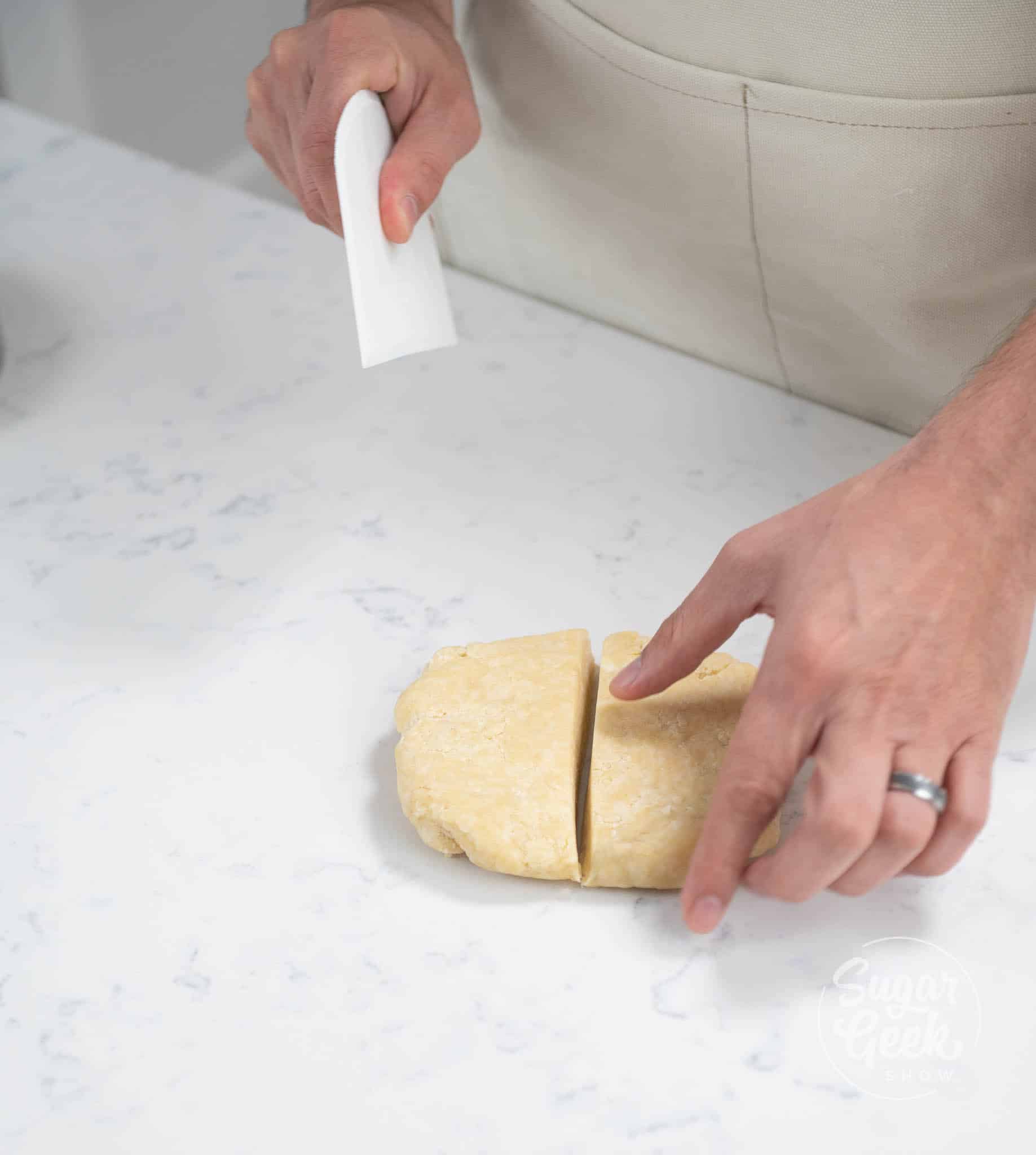 hands using scraper to cut dough in half