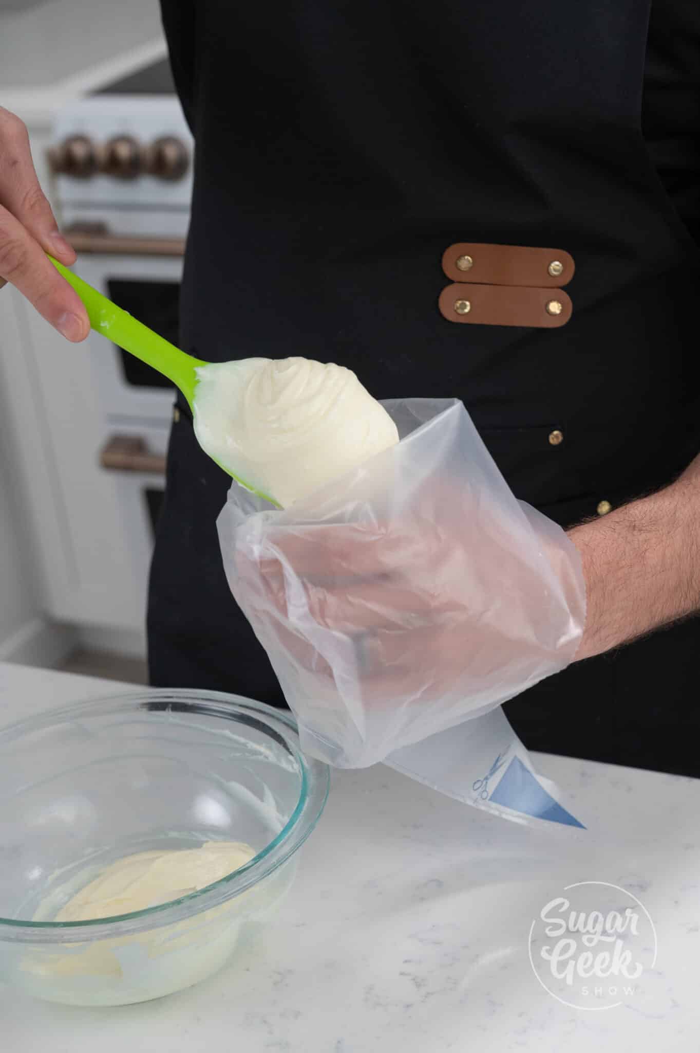 hand using spatula to place cream cheese filling into piping bag.