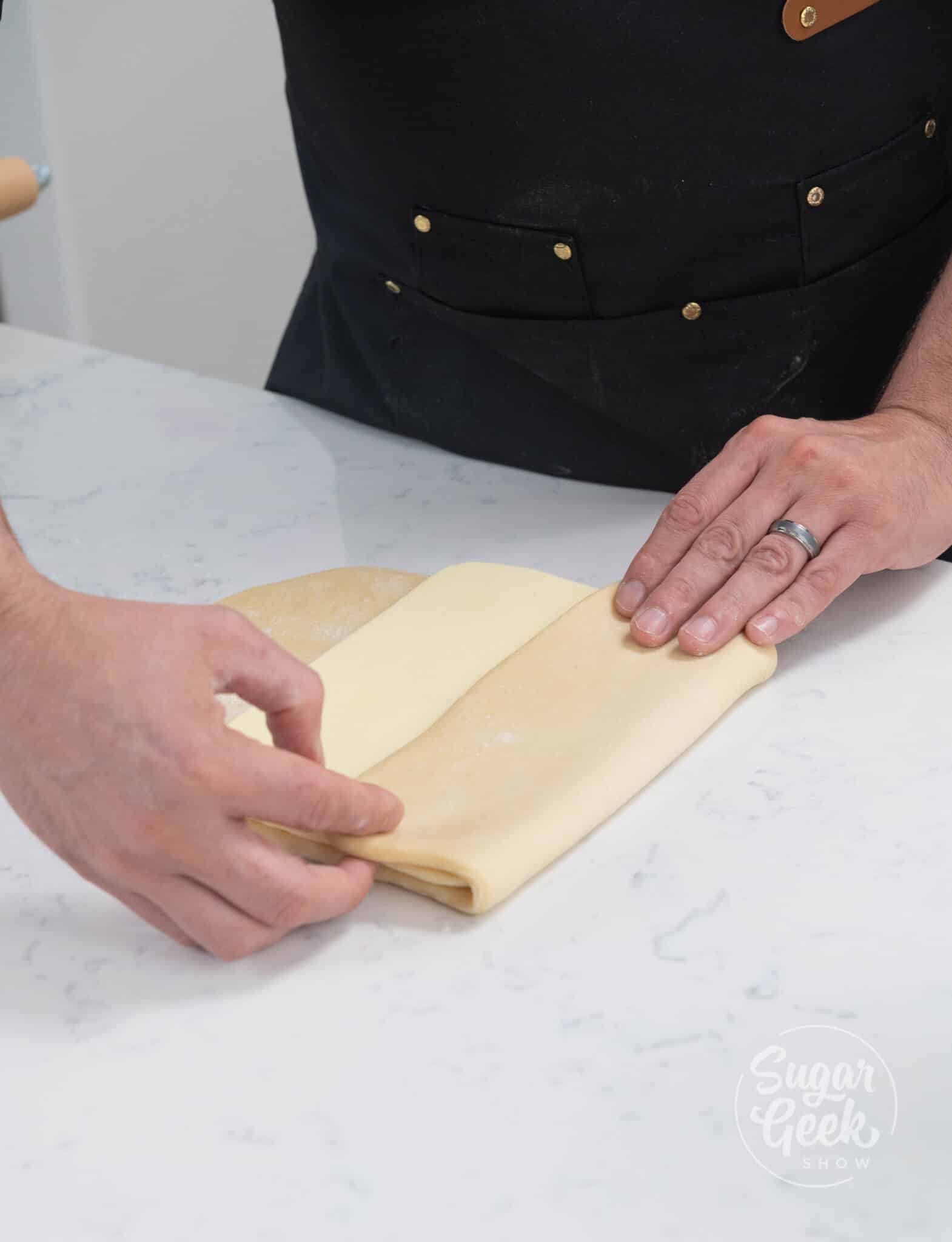 hands folding dough over butter.