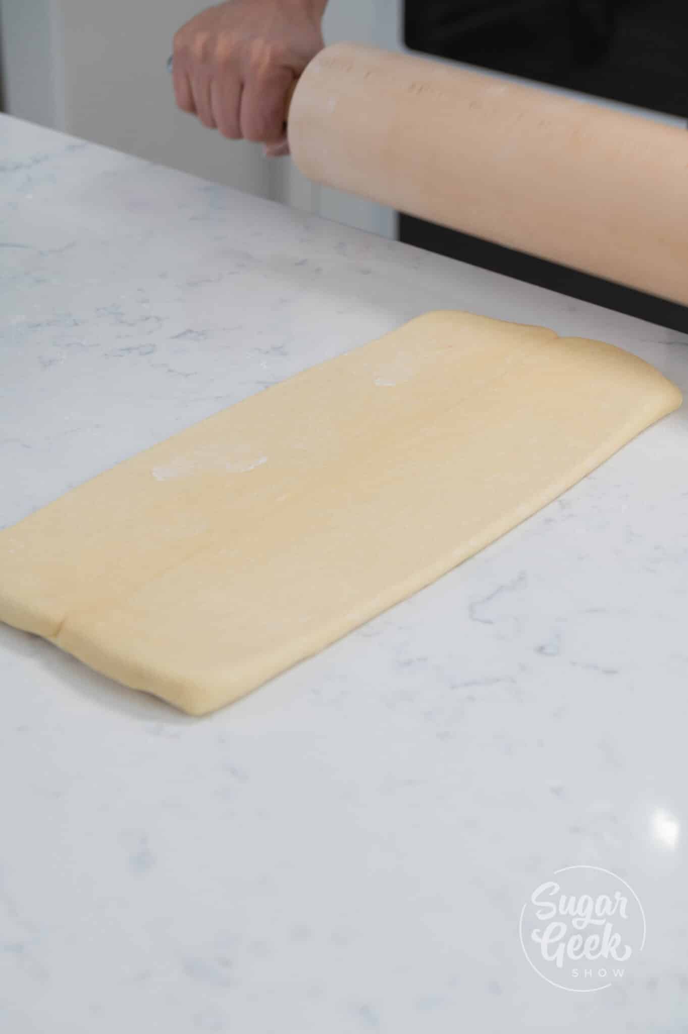hands rolling dough out with rolling pin
