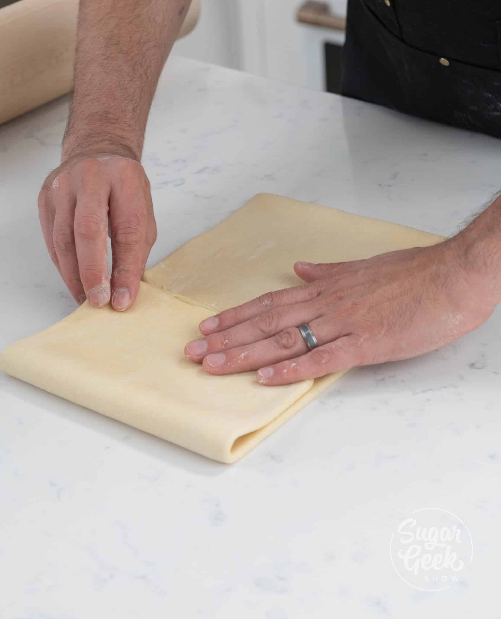 hands folding dough in half.